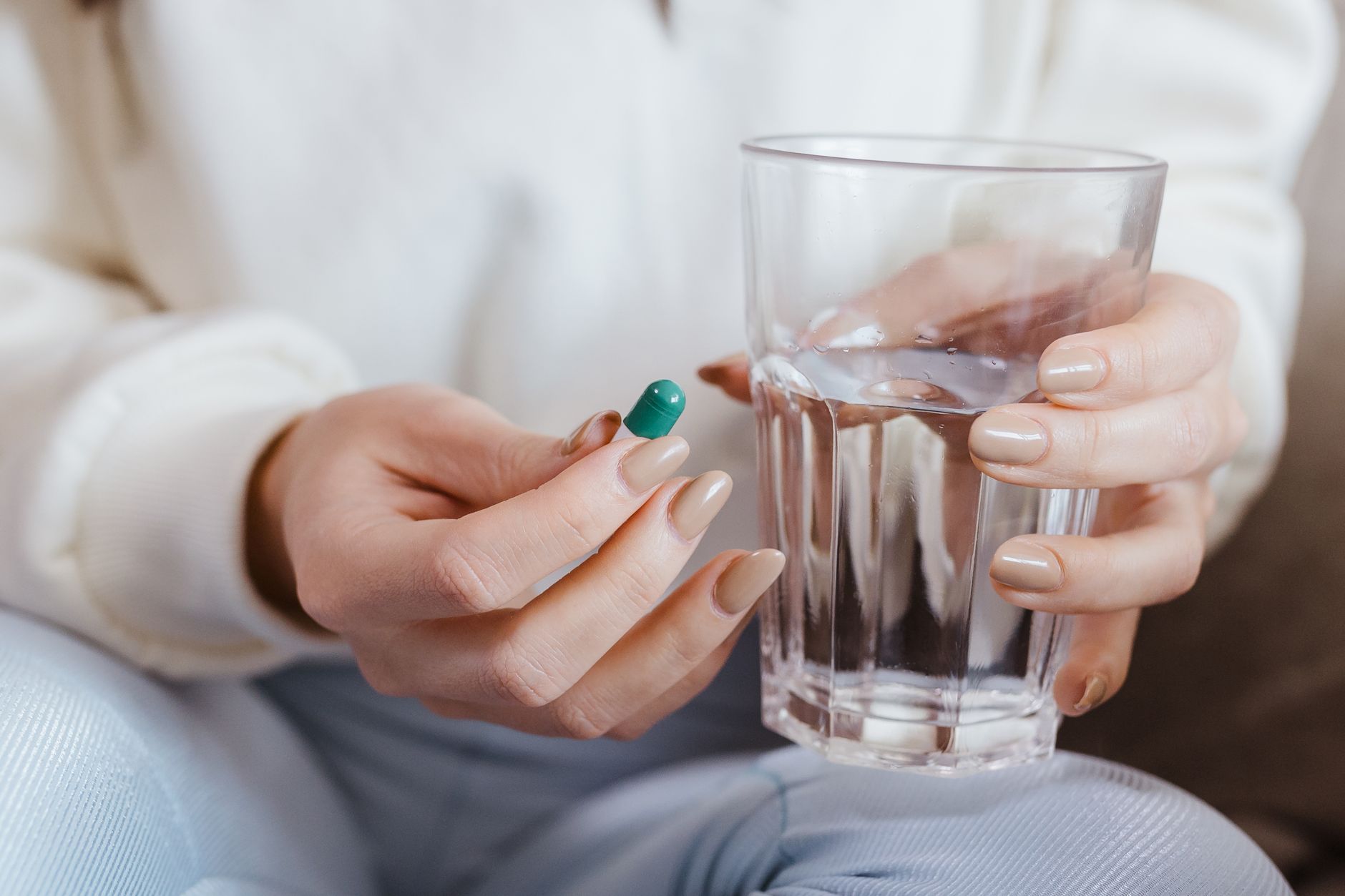 Pregnant woman taking a low-dose aspirin tablet with a glass of water