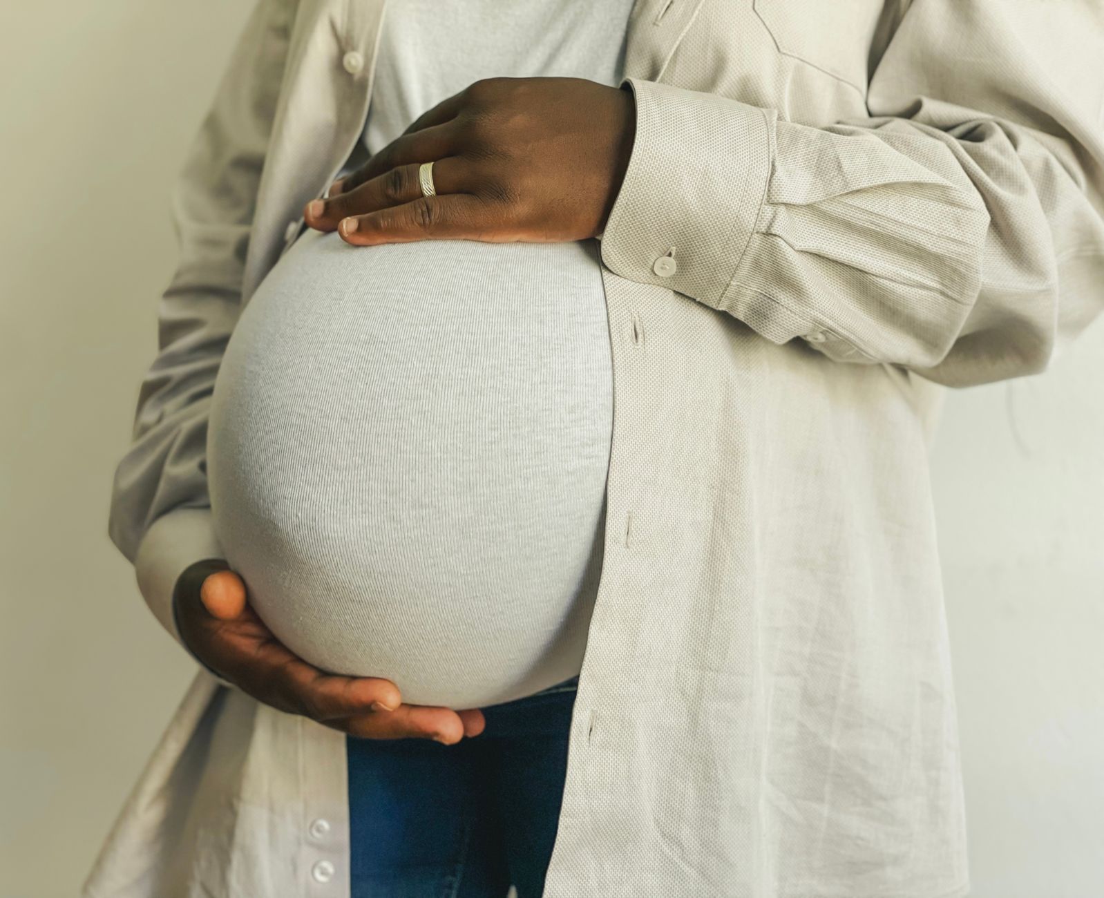 Close-up of a pregnant woman's hands showing mild swelling, with a wedding ring that feels tight