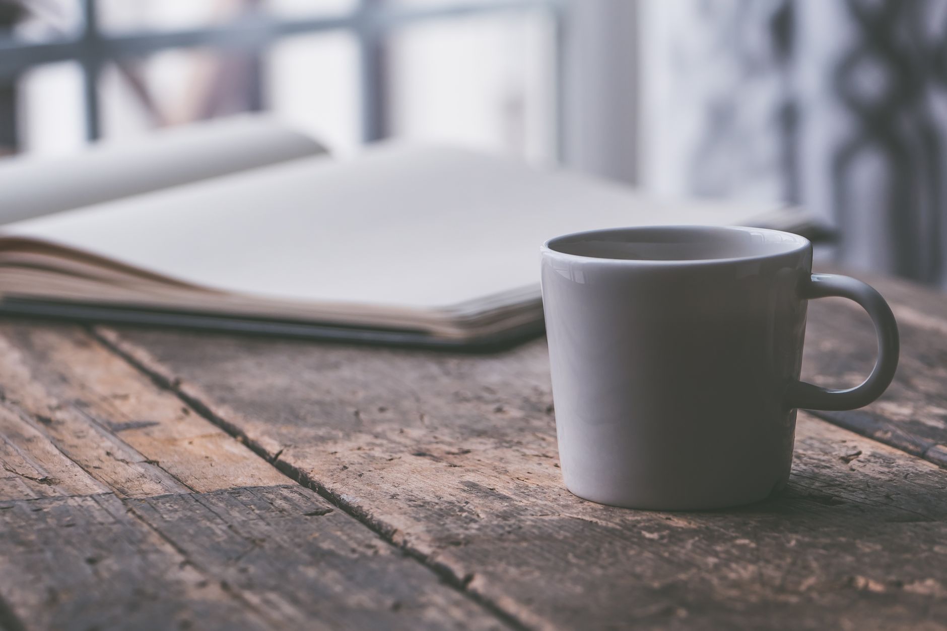 A close‑up of a therapist’s notebook with a pen, a cup of herbal tea, and a small potted plant on a wooden desk, indicating a supportive counseling environment