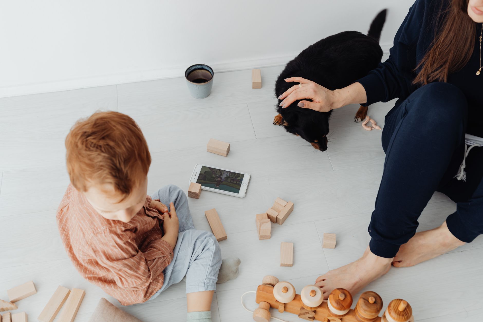 Parent filling out the M-CHAT questionnaire on a tablet while a toddler plays nearby