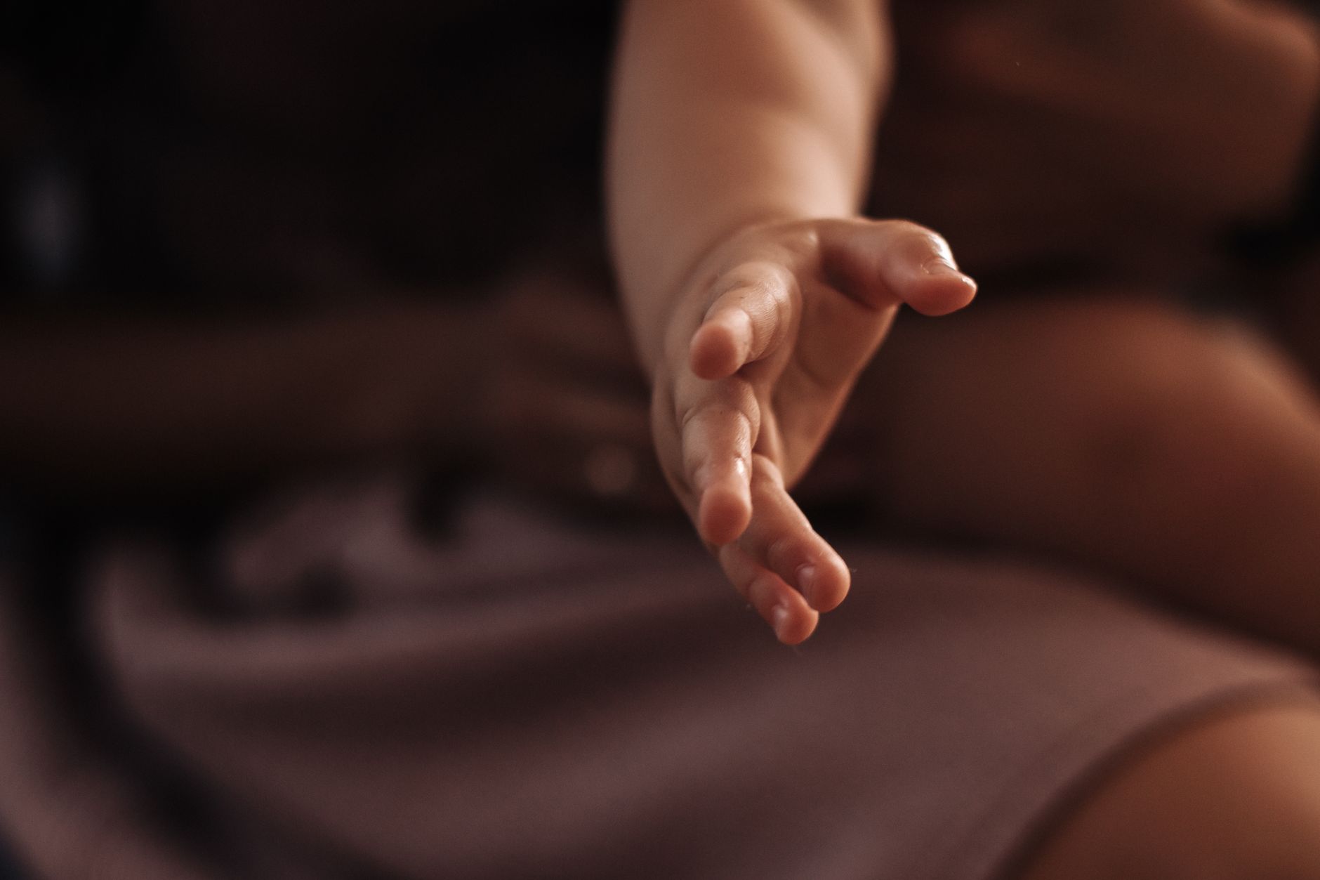 A baby's hand reaching for a water bottle, suggesting the importance of hydration.