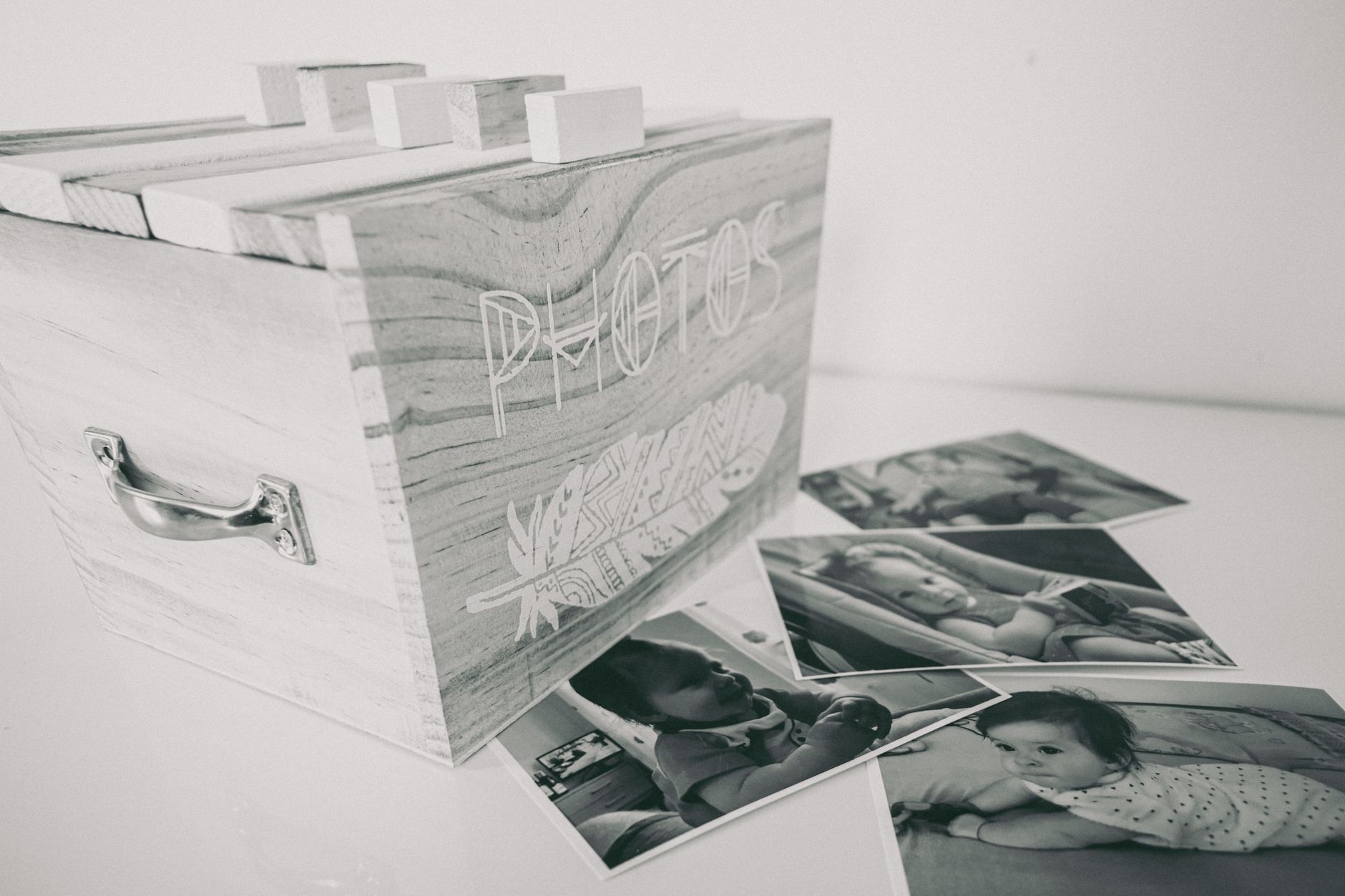 A wooden memory box filled with baby keepsakes, including a printed certificate, a handprint canvas, and a small stuffed animal