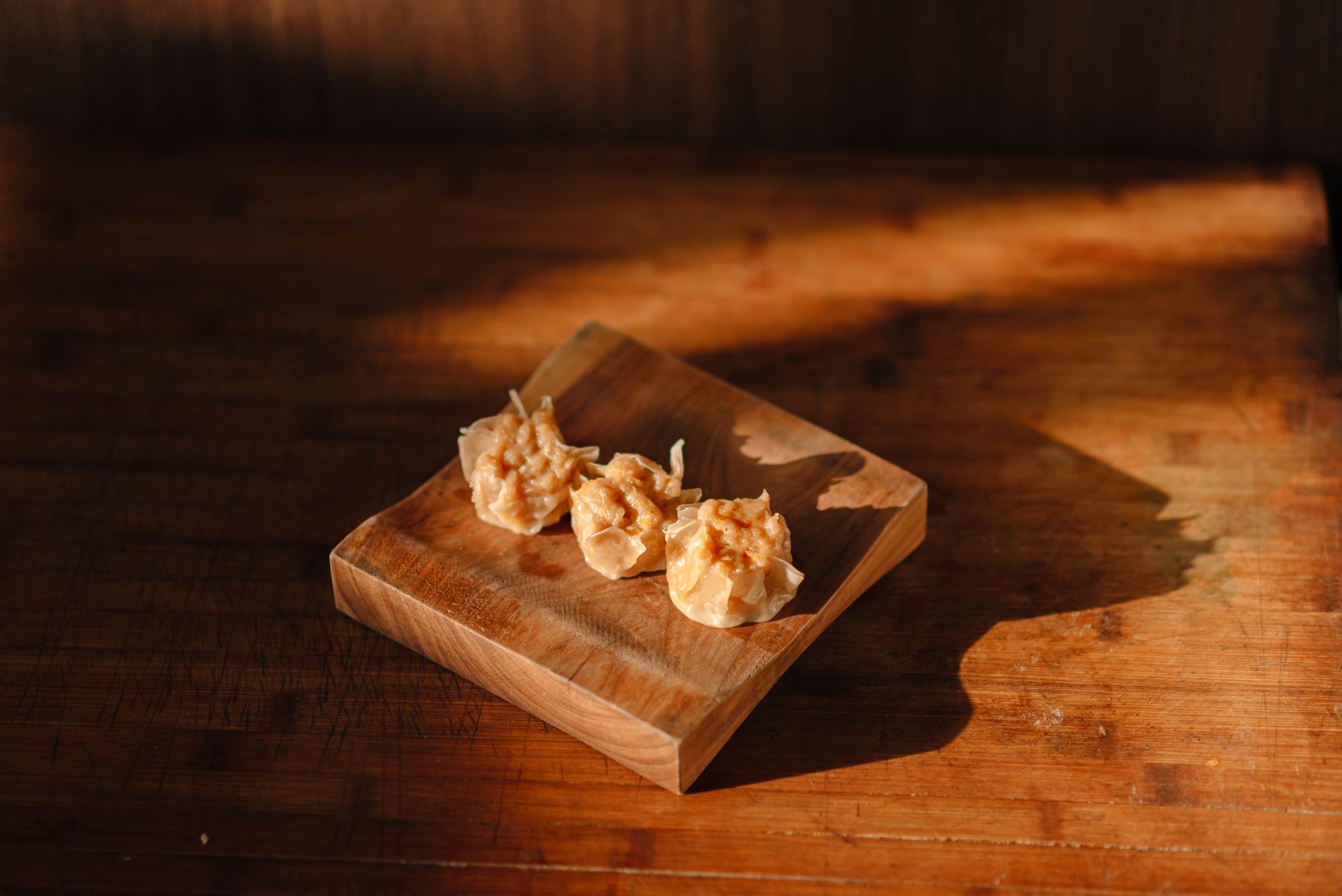 Close‑up of a toddler’s hand holding a soft steamed carrot stick, with a small bite‑size portion highlighted against a wooden cutting board