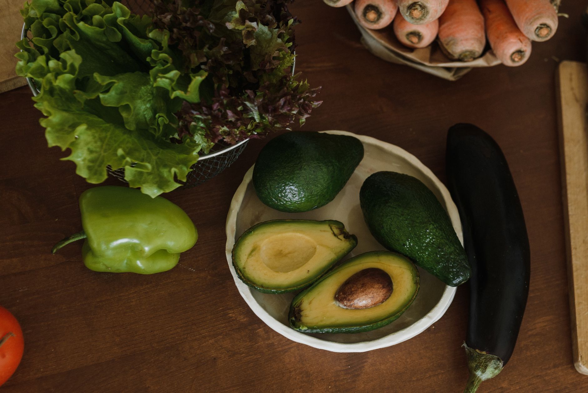 A calm kitchen scene with a high chair, a bowl of soft avocado chunks, a steaming pot of carrots, and a tablet displaying a food introduction tracker app