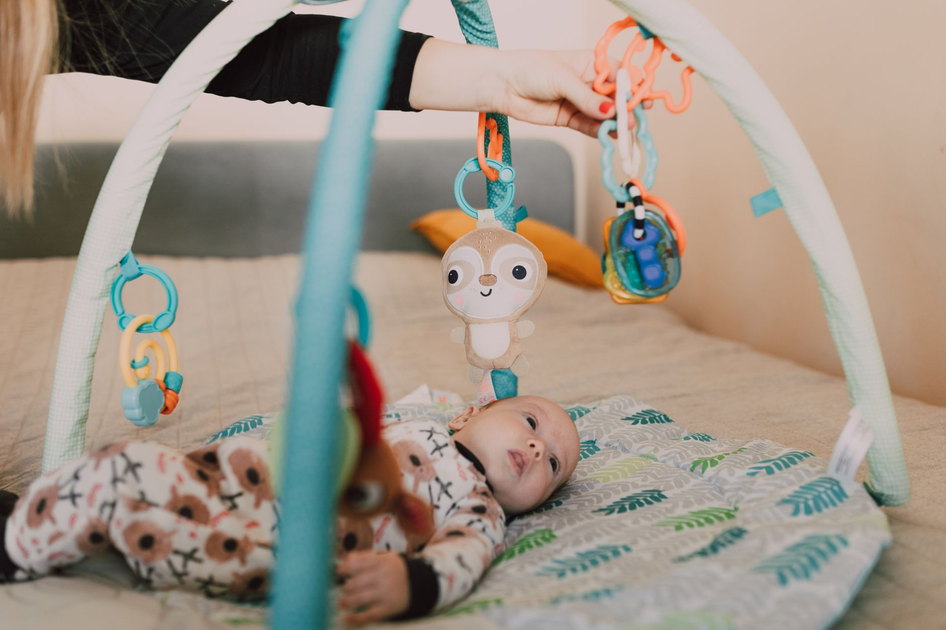 A six‑month‑old baby practicing tummy time on a bright, patterned mat with a smiling caregiver nearby
