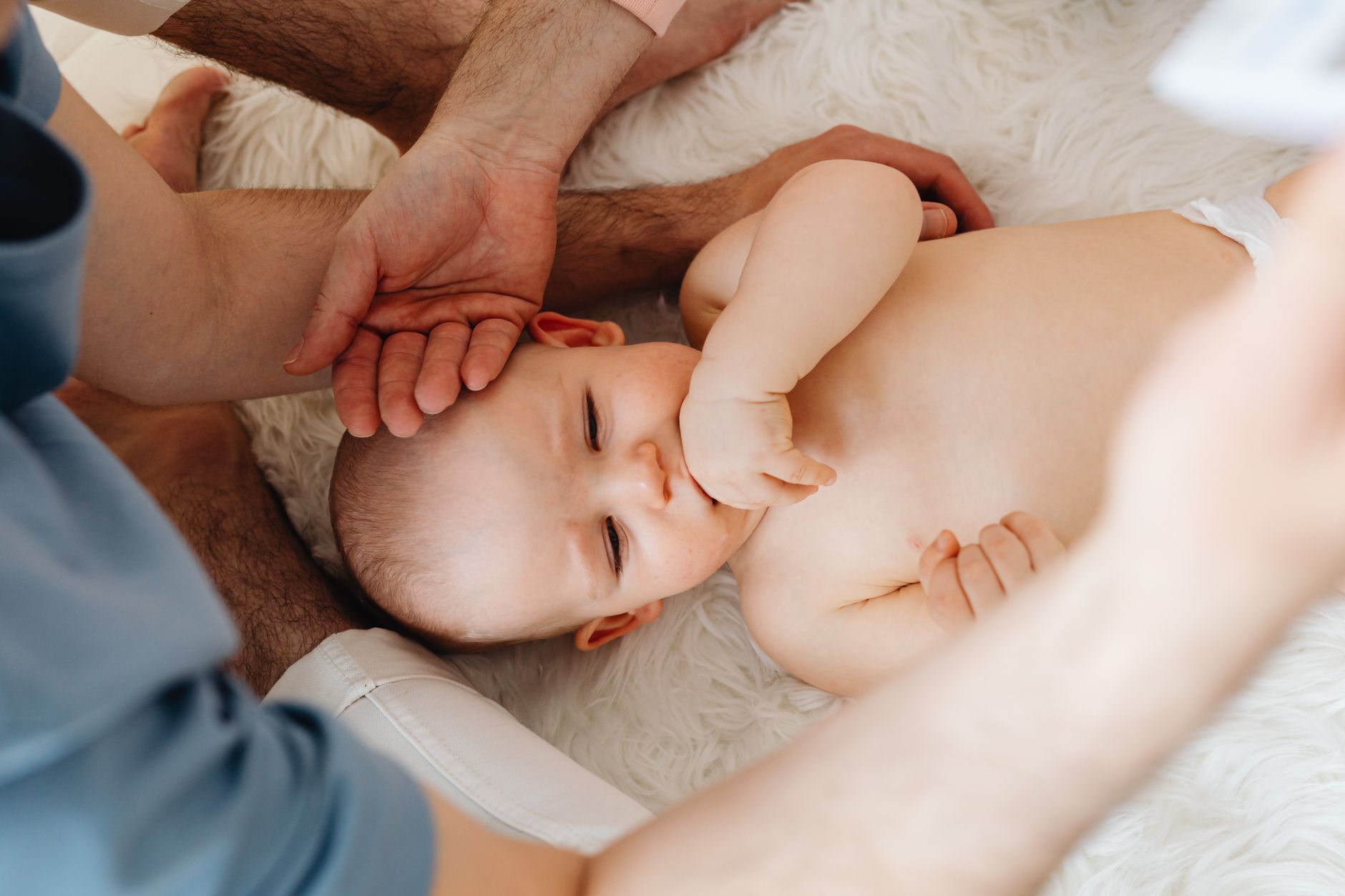 A smiling parent holding a baby’s hand while a healthcare professional prepares a small vaccine syringe on a clean tray