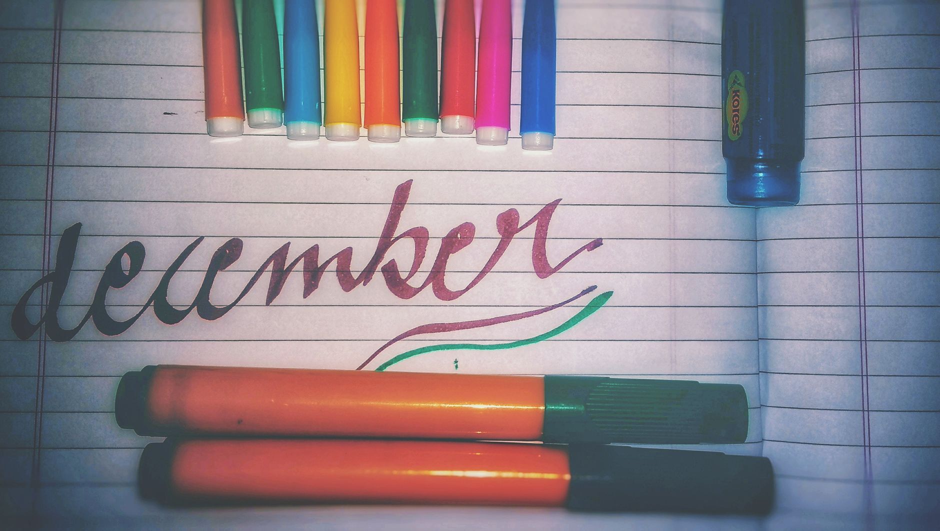 Close-up of a handwritten baby name list with colorful markers, a cup of tea, and a vintage numerology chart in the background