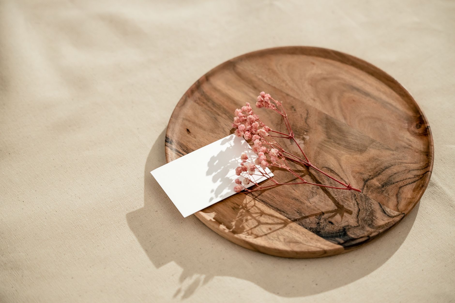 A wooden tray with two baby name cards side by side, one labeled 'Eleanor' and the other 'Eden', soft daylight highlighting the cards