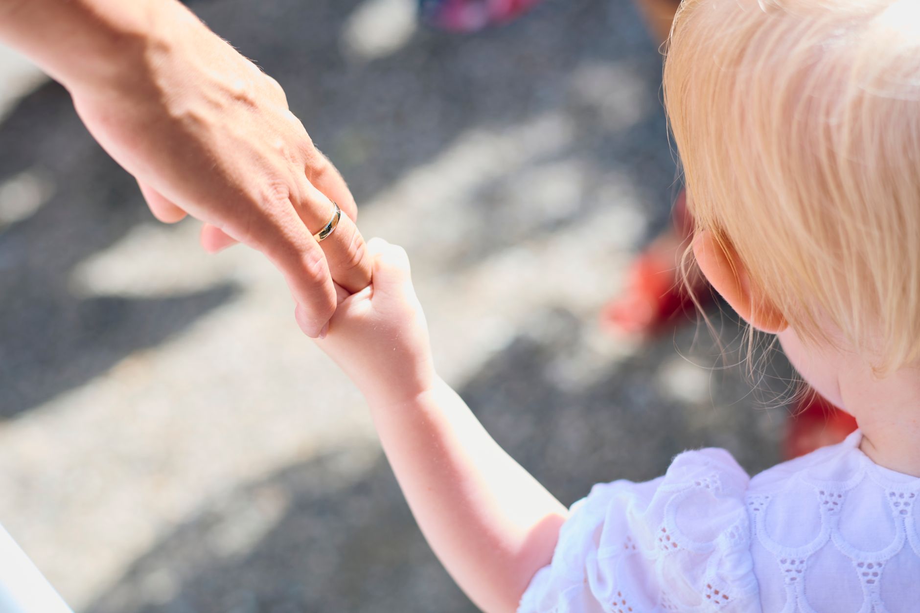 Preschooler holding a parent's hand while crossing a driveway