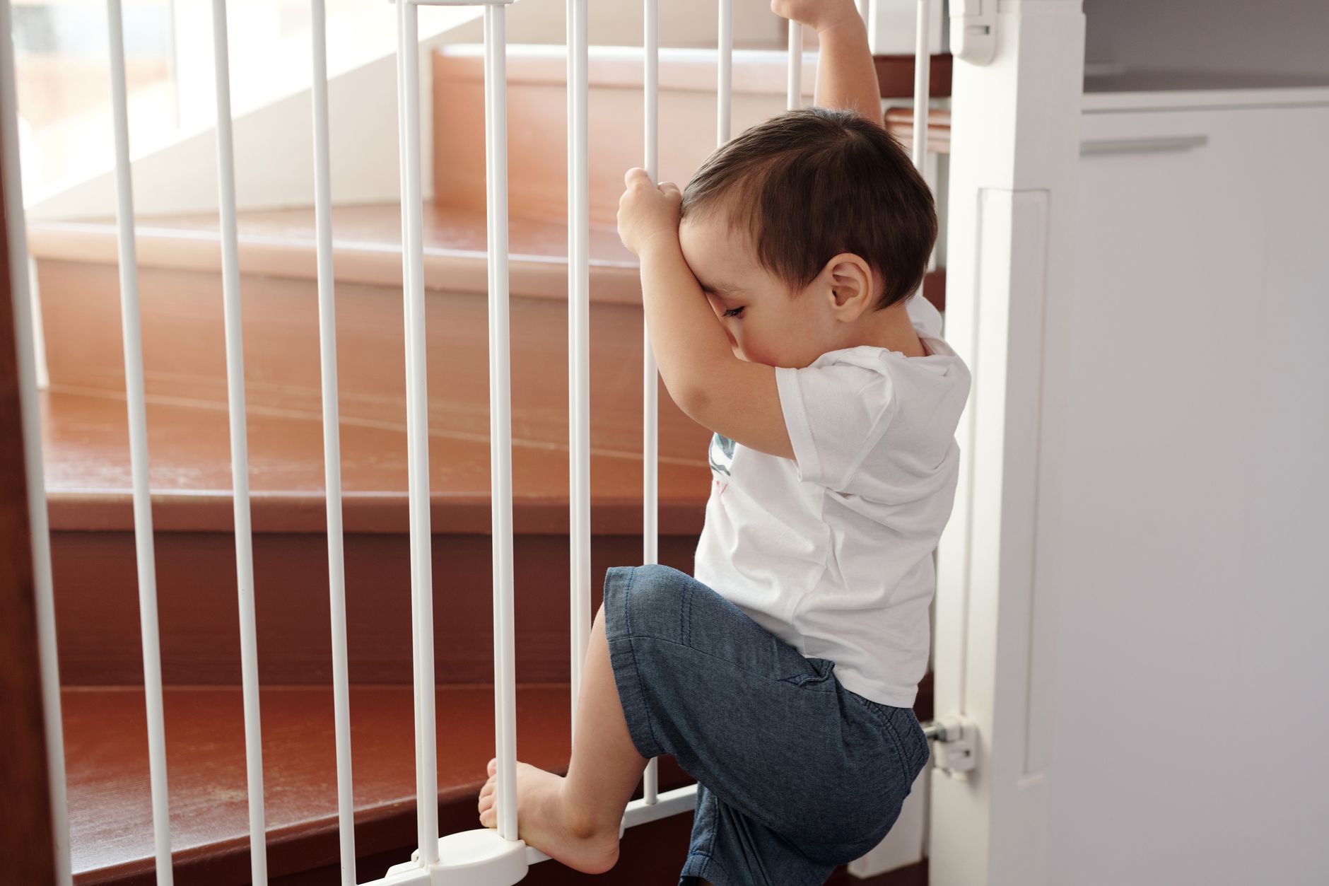 Baby crawling near a secured baby gate at the top of stairs