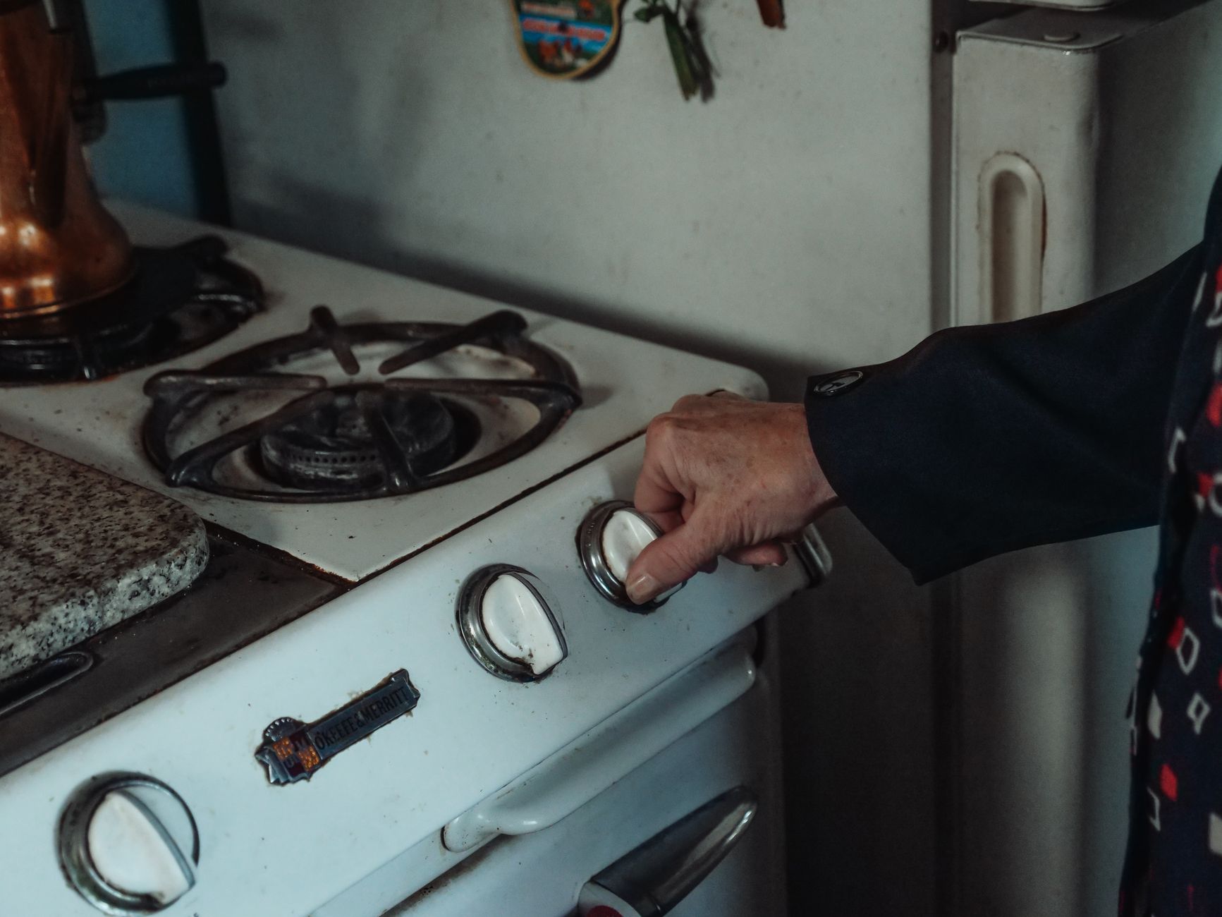Close-up of a parent installing a stove knob cover on a kitchen stove.