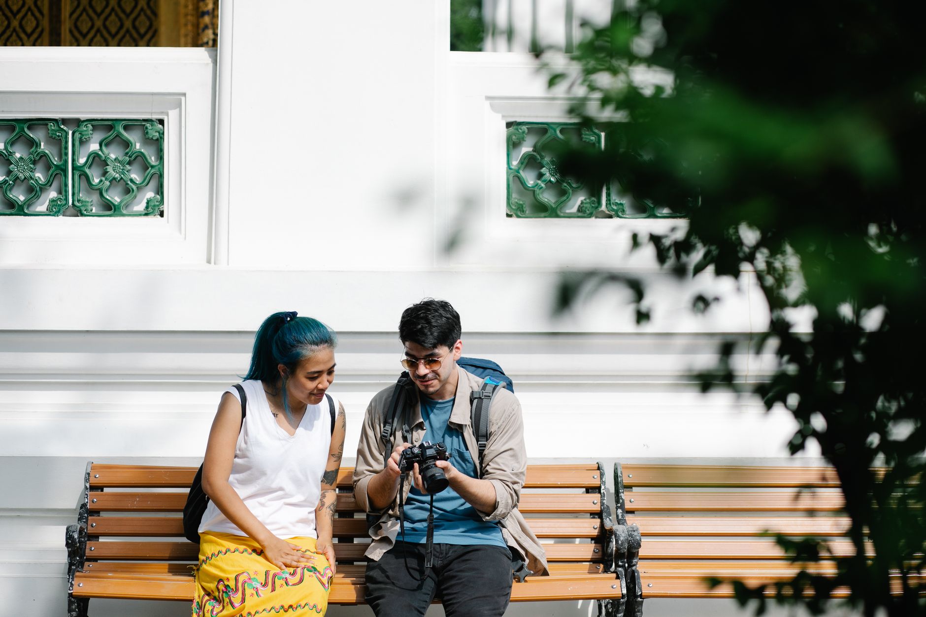 A couple sitting on a balcony with a laptop, journal, and camera capturing their babymoon memories