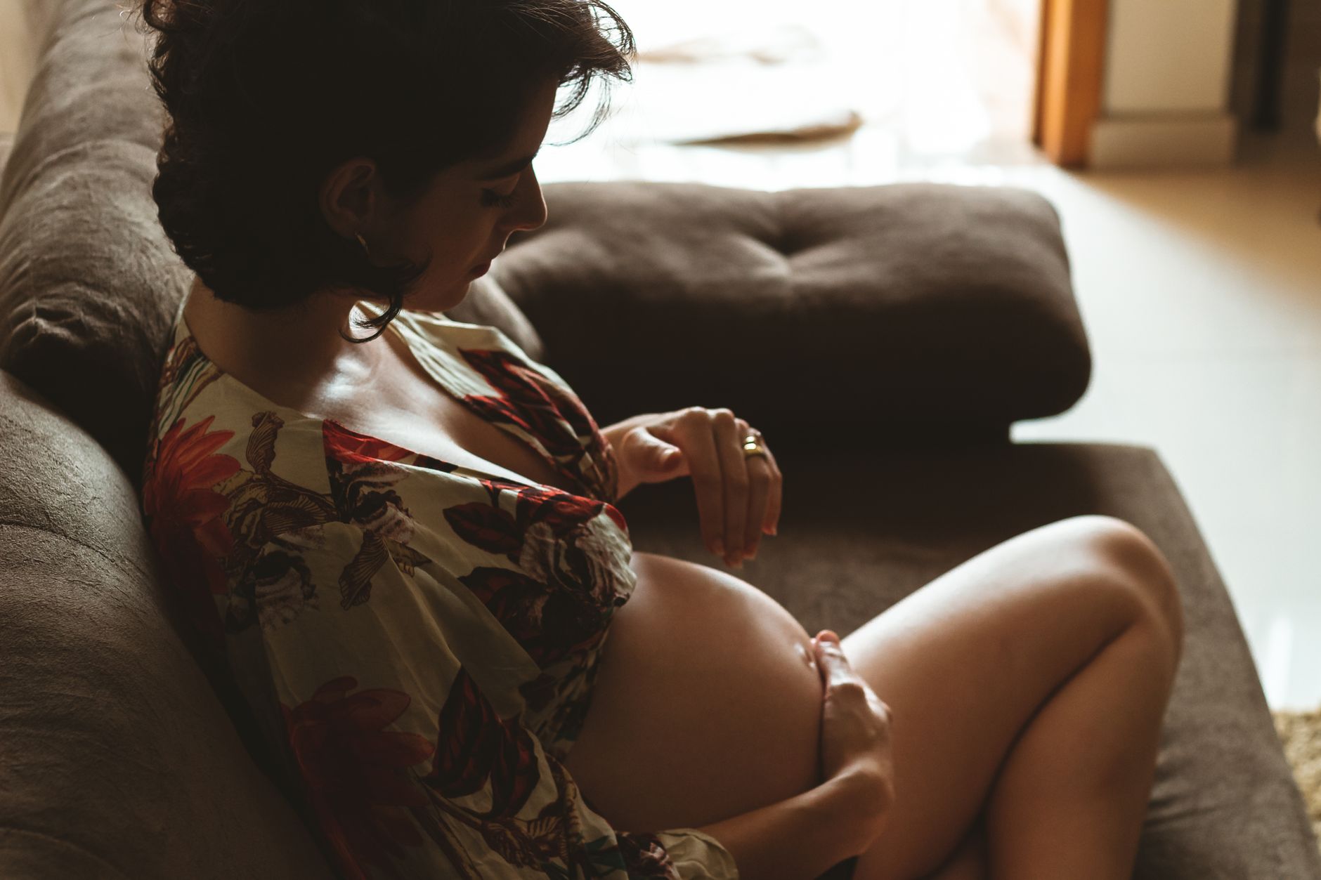 Pregnant woman sitting on couch feeling kicks