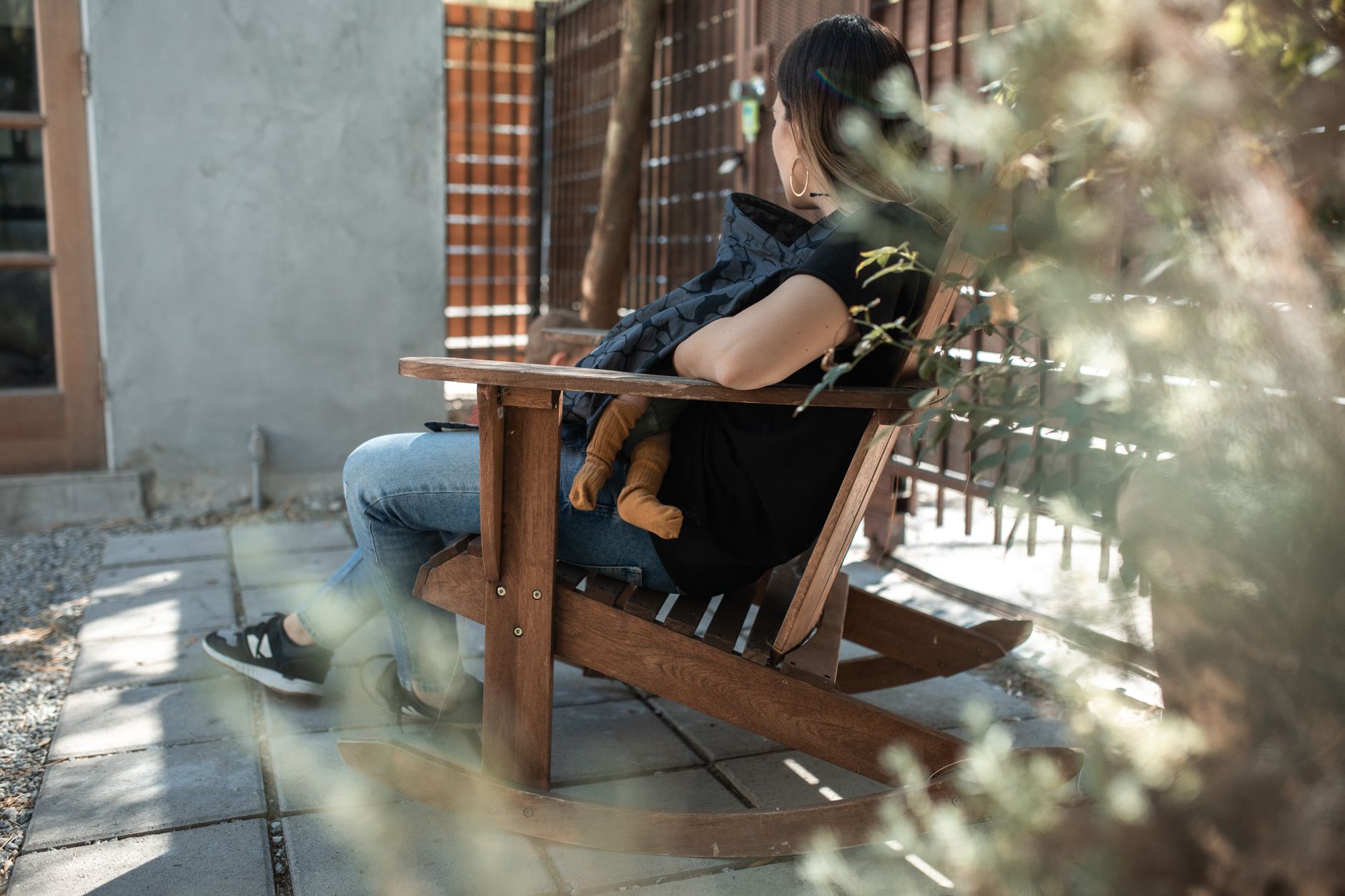 A mother gently rocking a newborn in a soft fabric rocking chair, low natural light creating a calm atmosphere