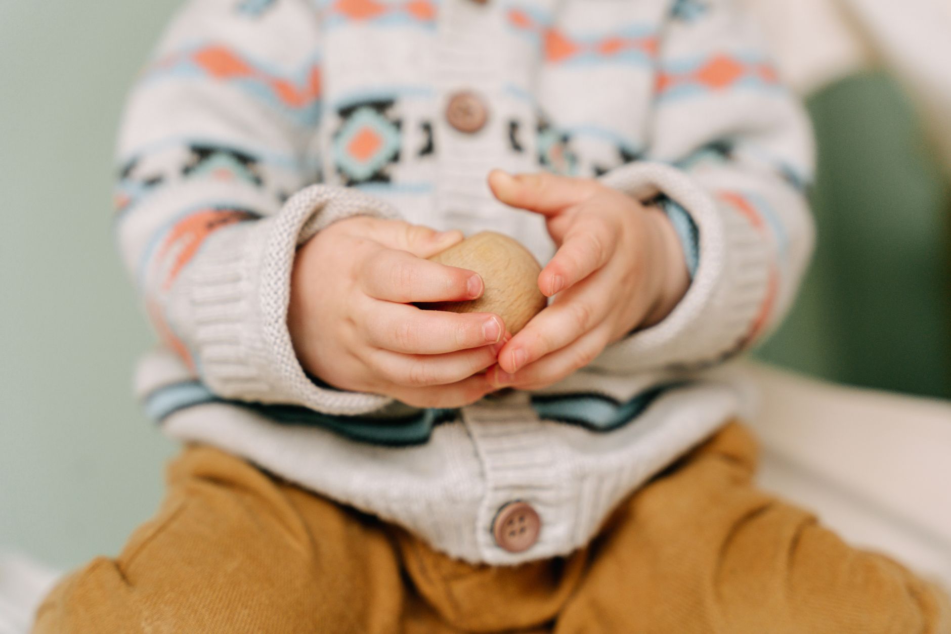 A baby holding a chilled silicone teething ring with a soft smile, natural daylight highlighting the gentle texture