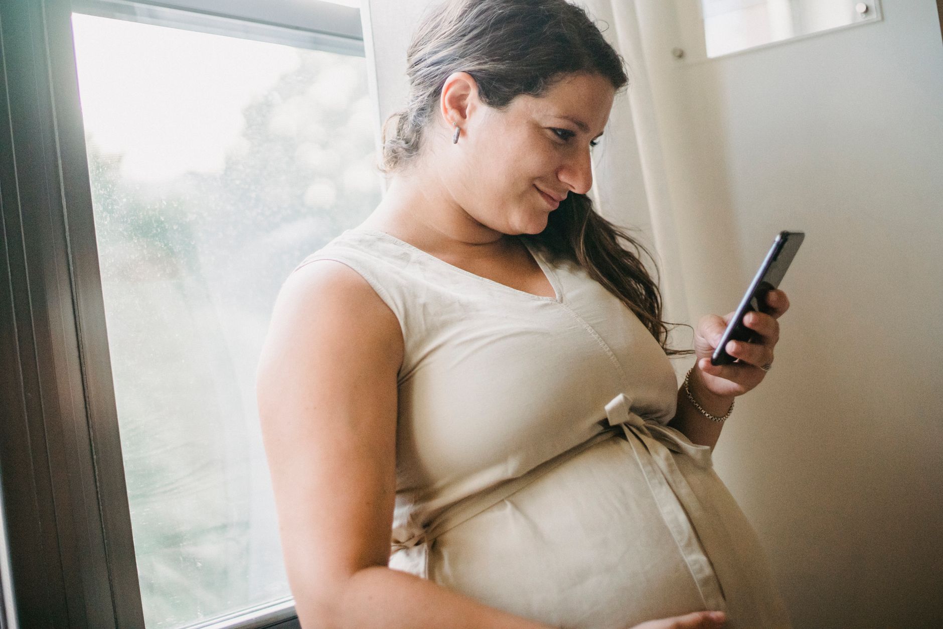 Pregnant woman sitting on couch with laptop, smiling while watching educational content