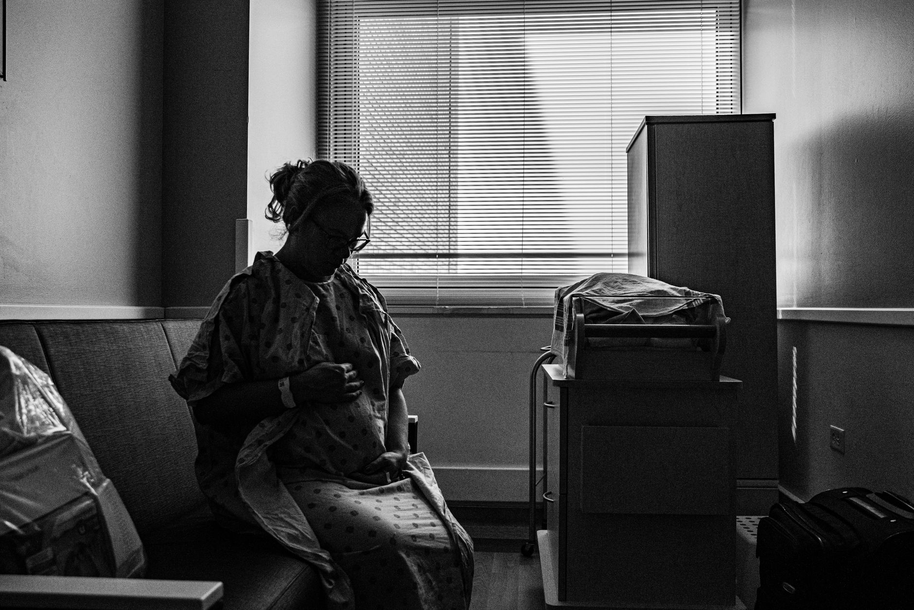 Pregnant woman sitting comfortably on a hospital chair, sipping water while a sonographer prepares the ultrasound probe