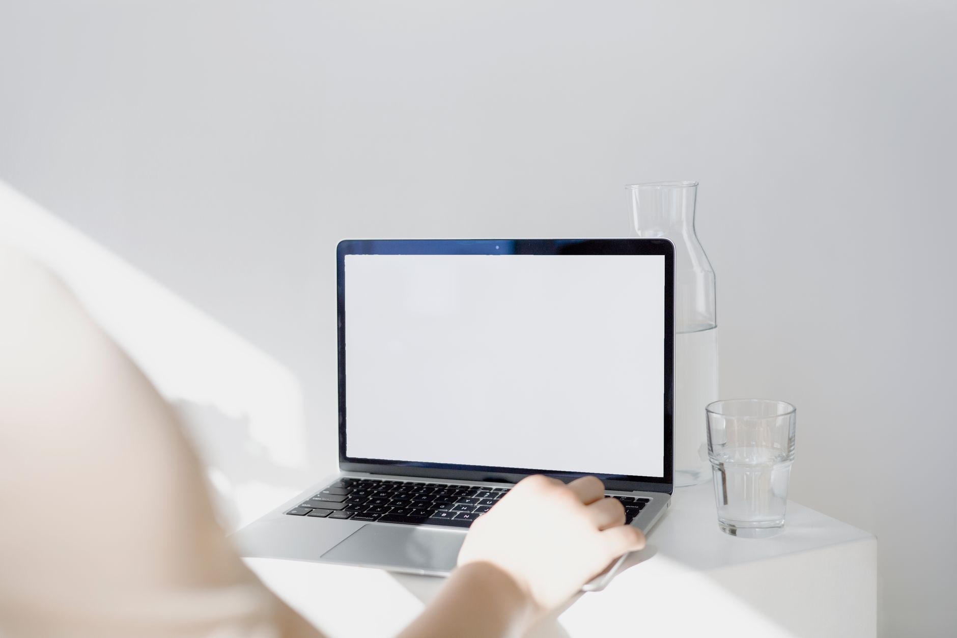 A portable electric breast pump sitting on a tidy office desk beside a laptop, a water bottle and a small bowl of almonds, illustrating a convenient workplace lactation setup