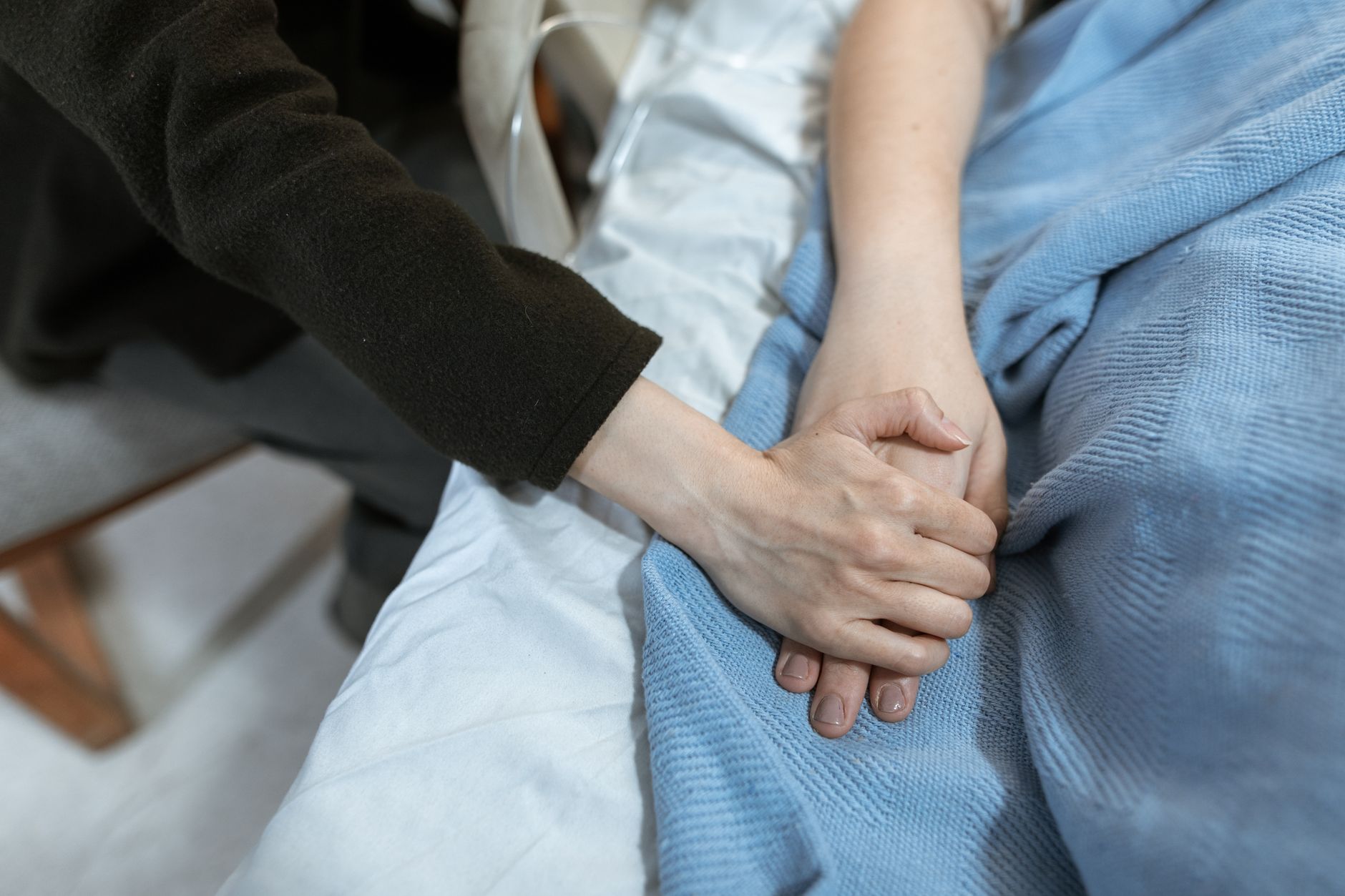 A pregnant woman resting on a hospital bed with a supportive partner, soft lighting, and a comforting blanket