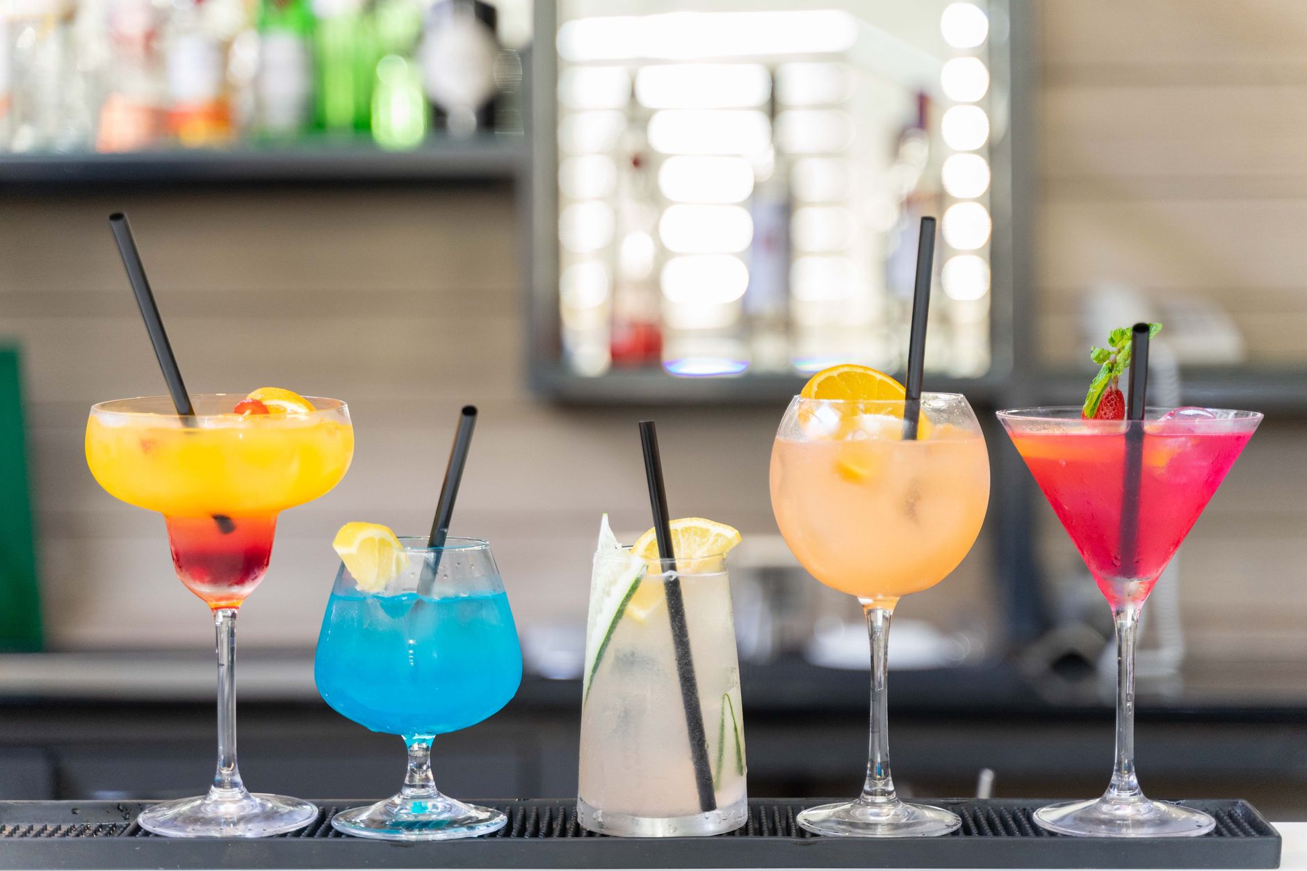 A variety of colorful mocktails in elegant glasses on a bar top, garnished with fresh fruit and herbs, inviting and refreshing.