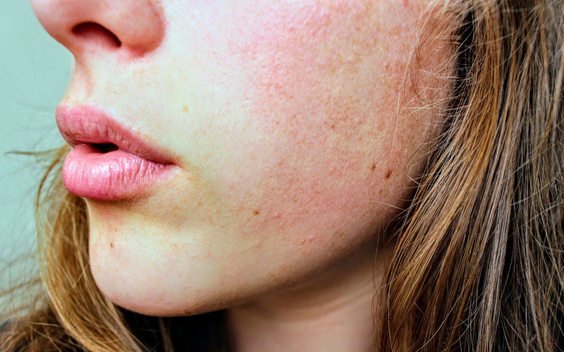 Close‑up of a gentle facial mask being applied to a pregnant woman's cheek, showing a smooth, creamy texture without visible irritation