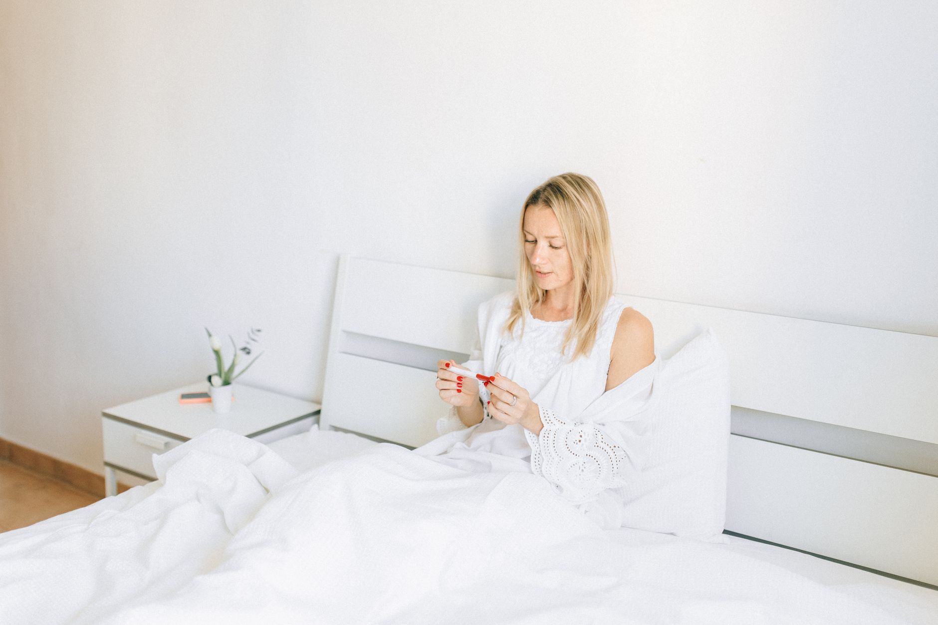 A woman holding an ovulation predictor kit, looking at the results with a hopeful expression