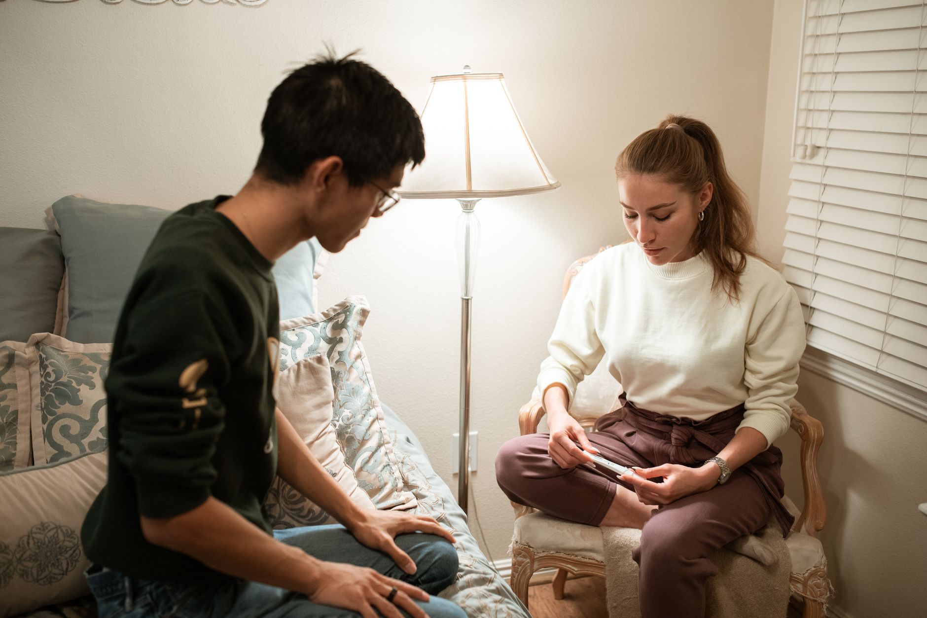 A calm bedroom scene with a pregnant woman holding a positive pregnancy test, soft sunrise light streaming through curtains