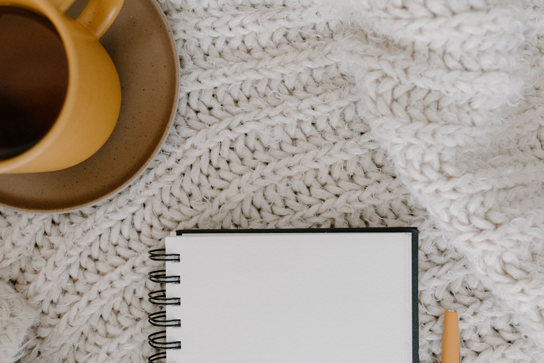 Close‑up of a pregnant woman’s hand resting on a tabletop with a cup of tea, a notebook showing cervical length numbers, soft natural light