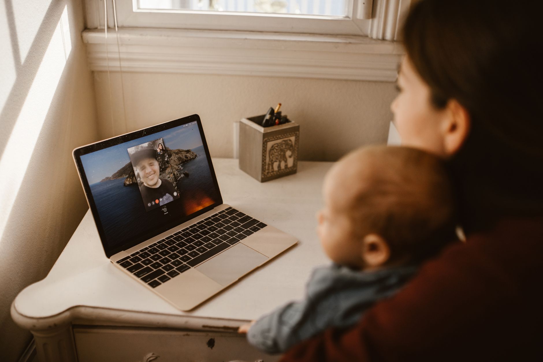 A laptop showing a video call with a group of moms smiling and chatting