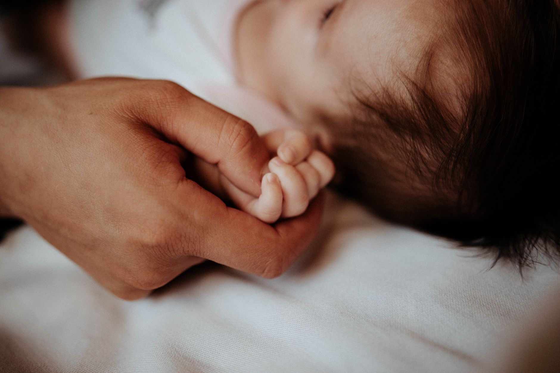 A parent offering a bottle to a baby, gentle and comforting interaction, bright kitchen setting