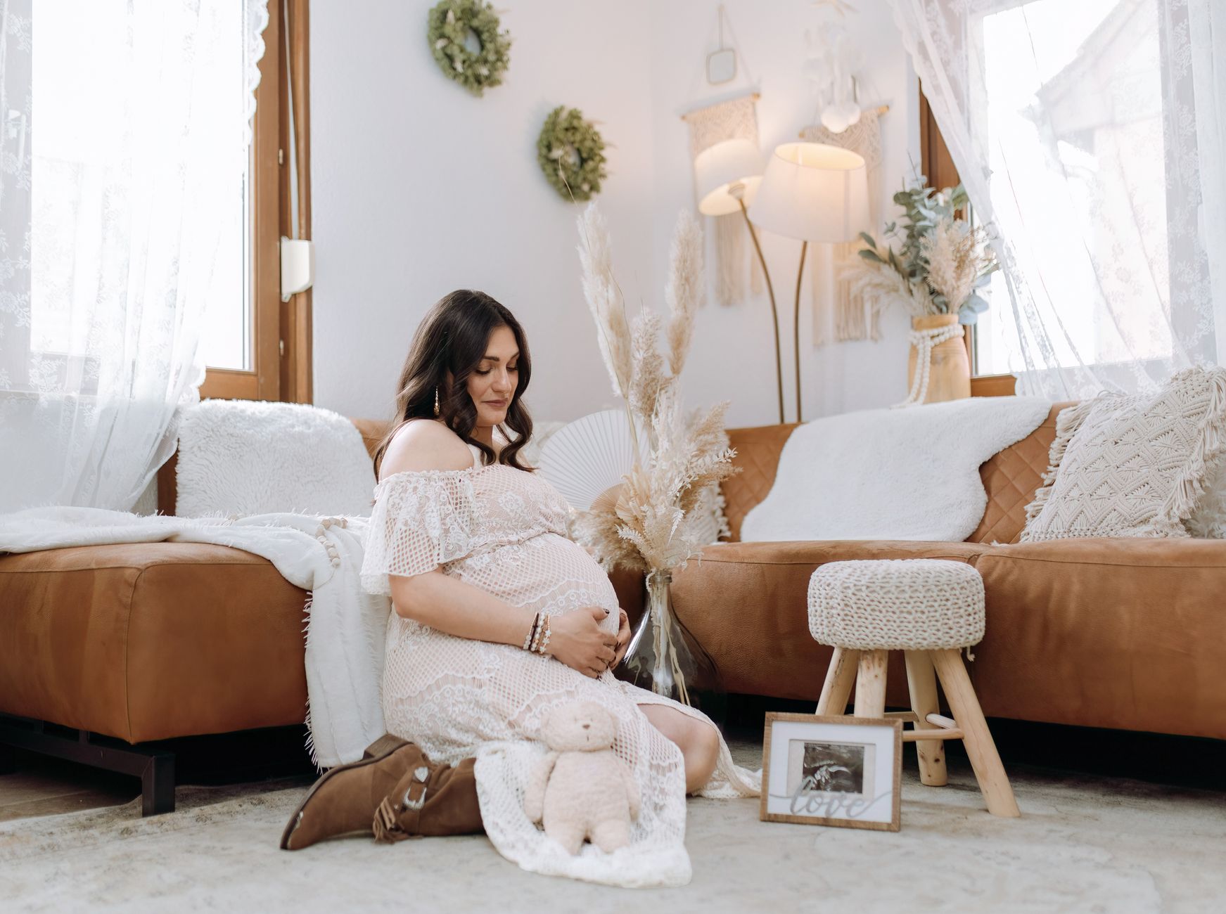 Pregnant woman resting on a couch with a soft blanket, a water bottle and a prenatal vitamin bottle nearby, sunlight streaming through a window