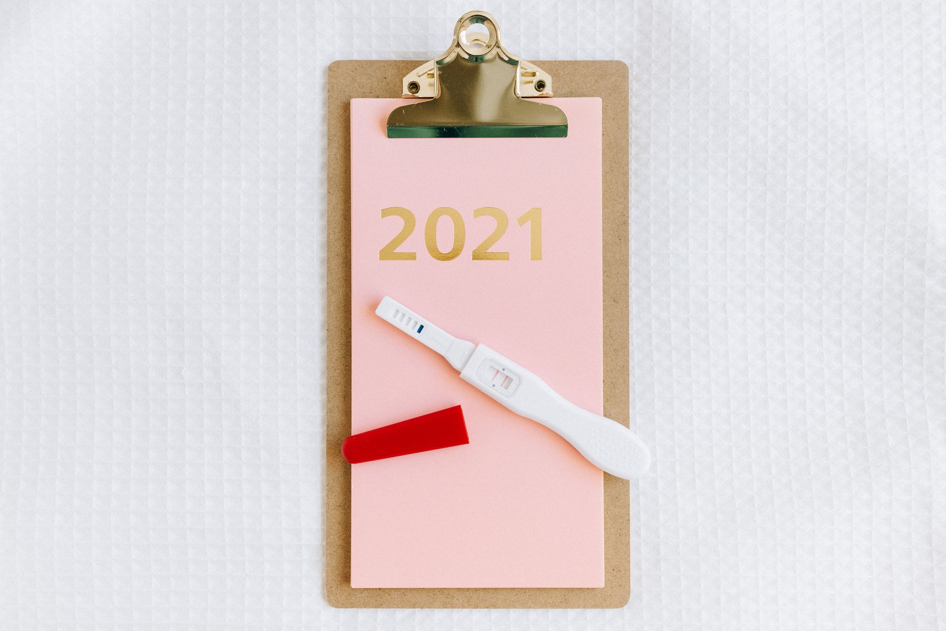 Hand holding a pregnancy test beside a lab notebook showing serial beta-hCG values decreasing over days