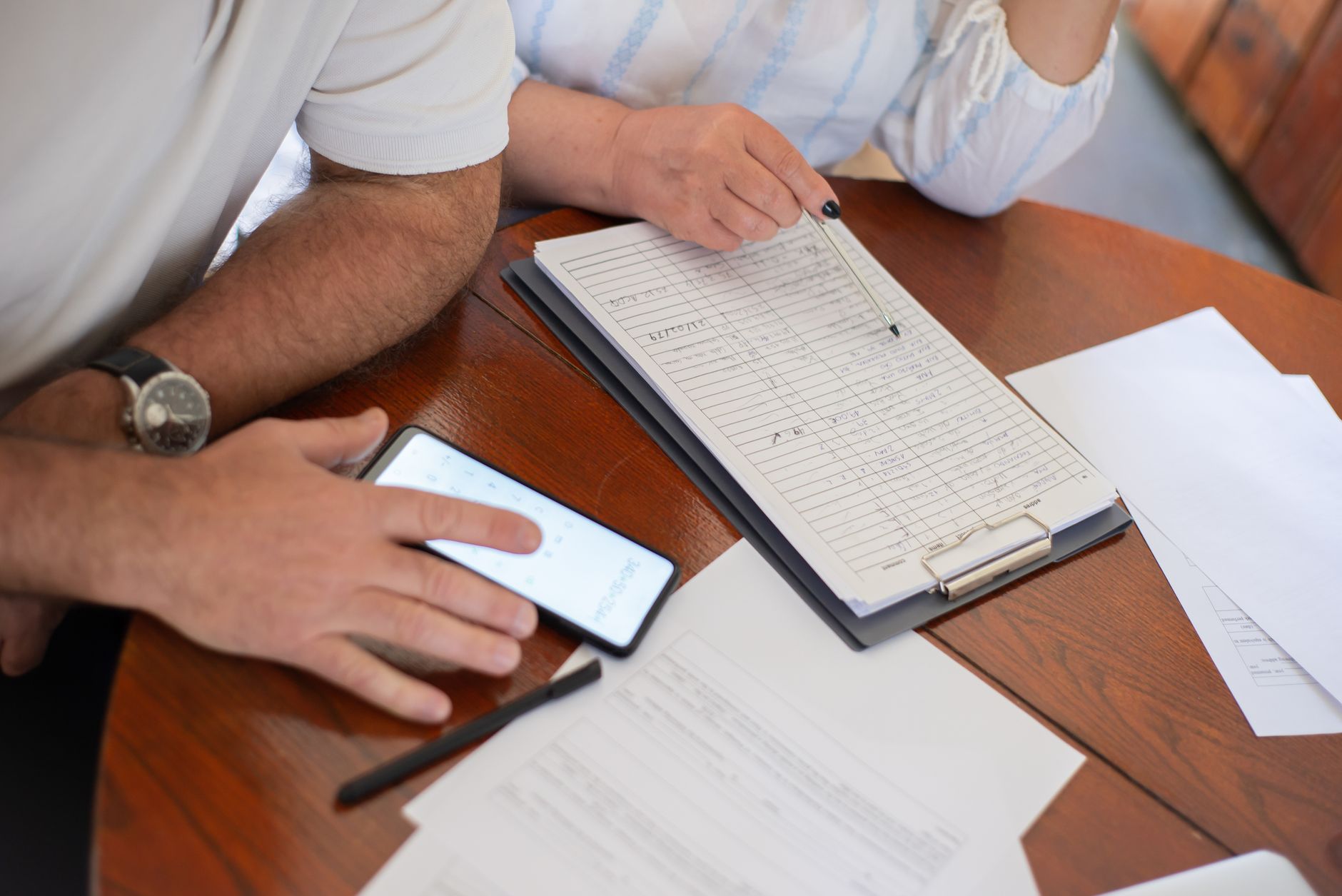 A couple reviewing a financial planner app on their phone with a baby monitor nearby