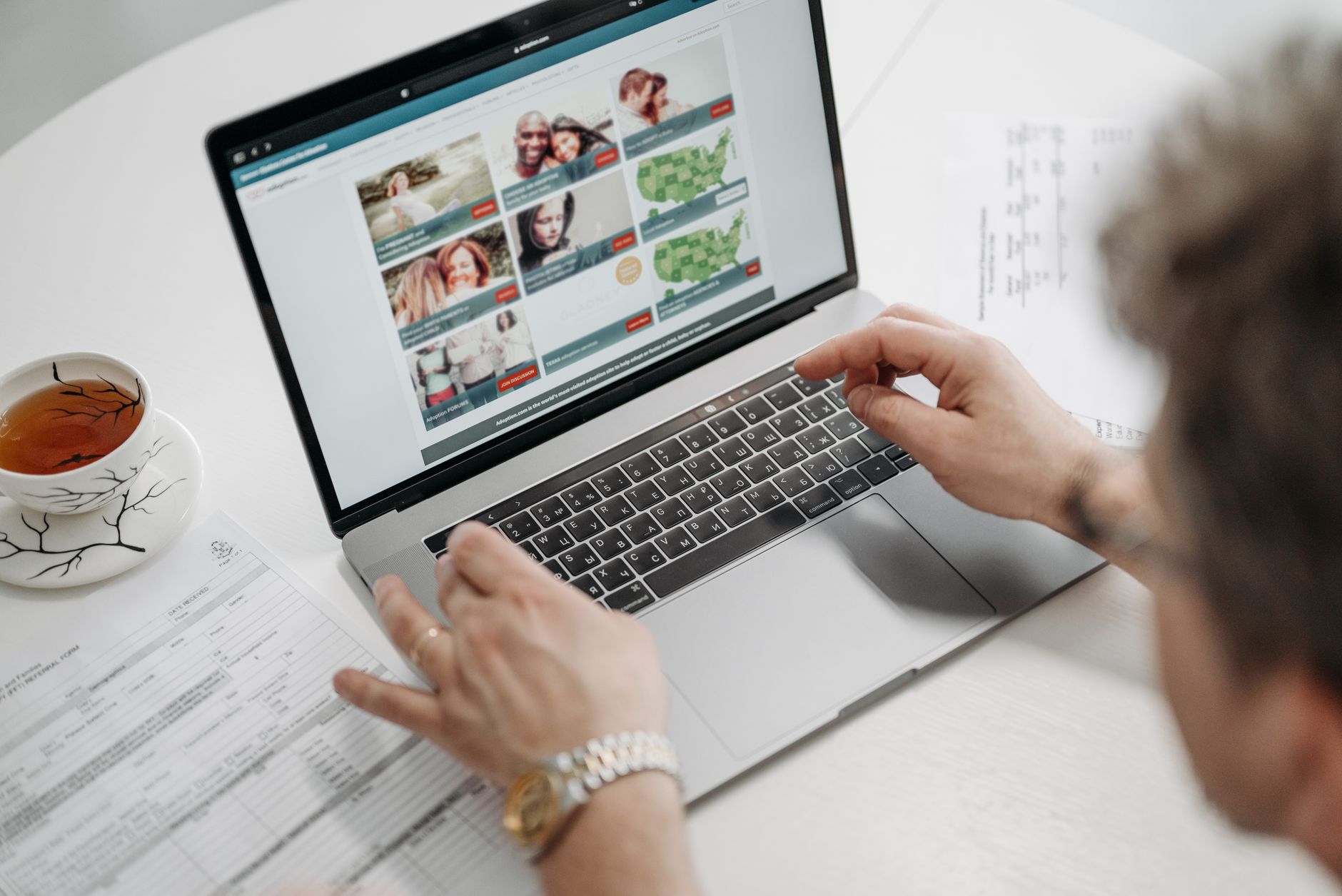 A map of the U.S. with state adoption cost labels and a couple researching on a laptop
