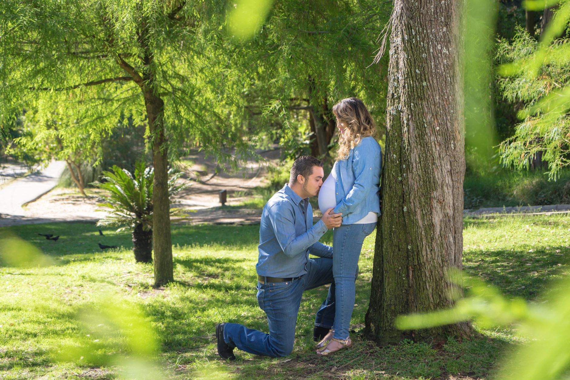 Pregnant woman walking in a park with a supportive partner, both wearing comfortable clothing; soft morning light, natural greenery, lifestyle photography