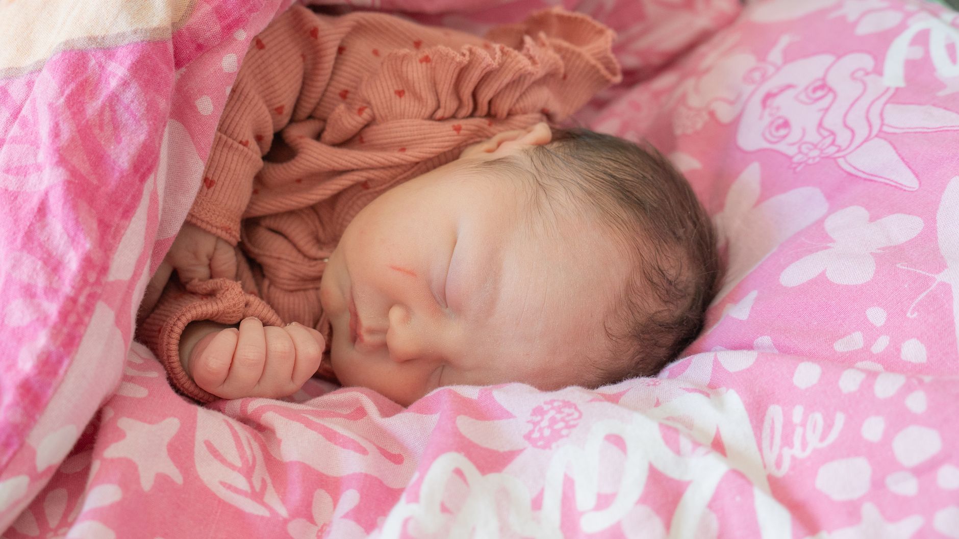 Close‑up of a preterm infant’s tiny hand grasping a soft blanket, gentle afternoon light, calm NICU setting