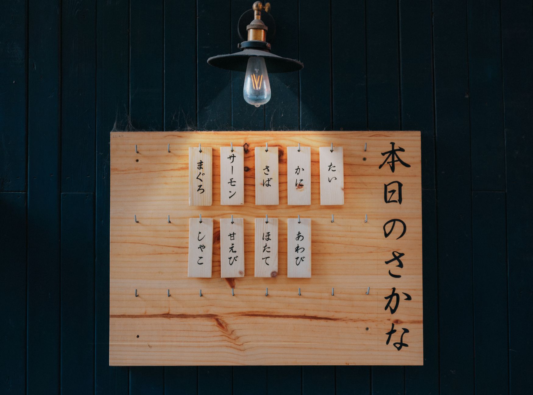 A cozy nursery corner with a wooden name board displaying a cultural baby name in elegant script, soft pastel lighting