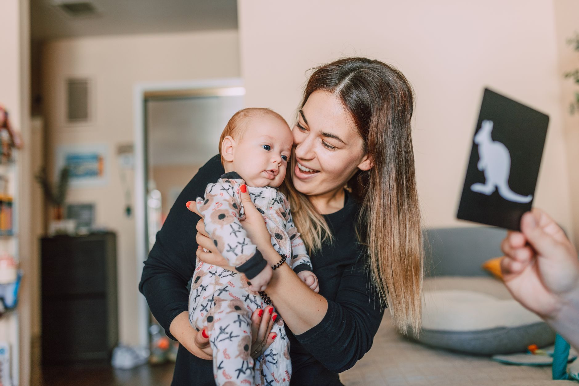 A mom sitting on a couch with her baby, looking at a photo album of new family traditions