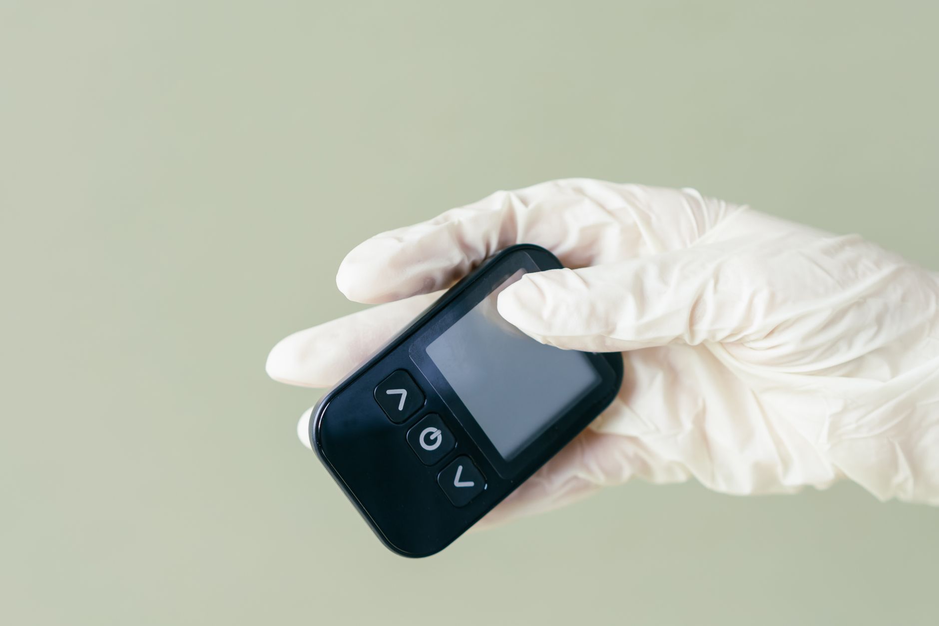 Neonate lying on a warm incubator blanket while a nurse checks a heel‑stick glucose level with a handheld meter