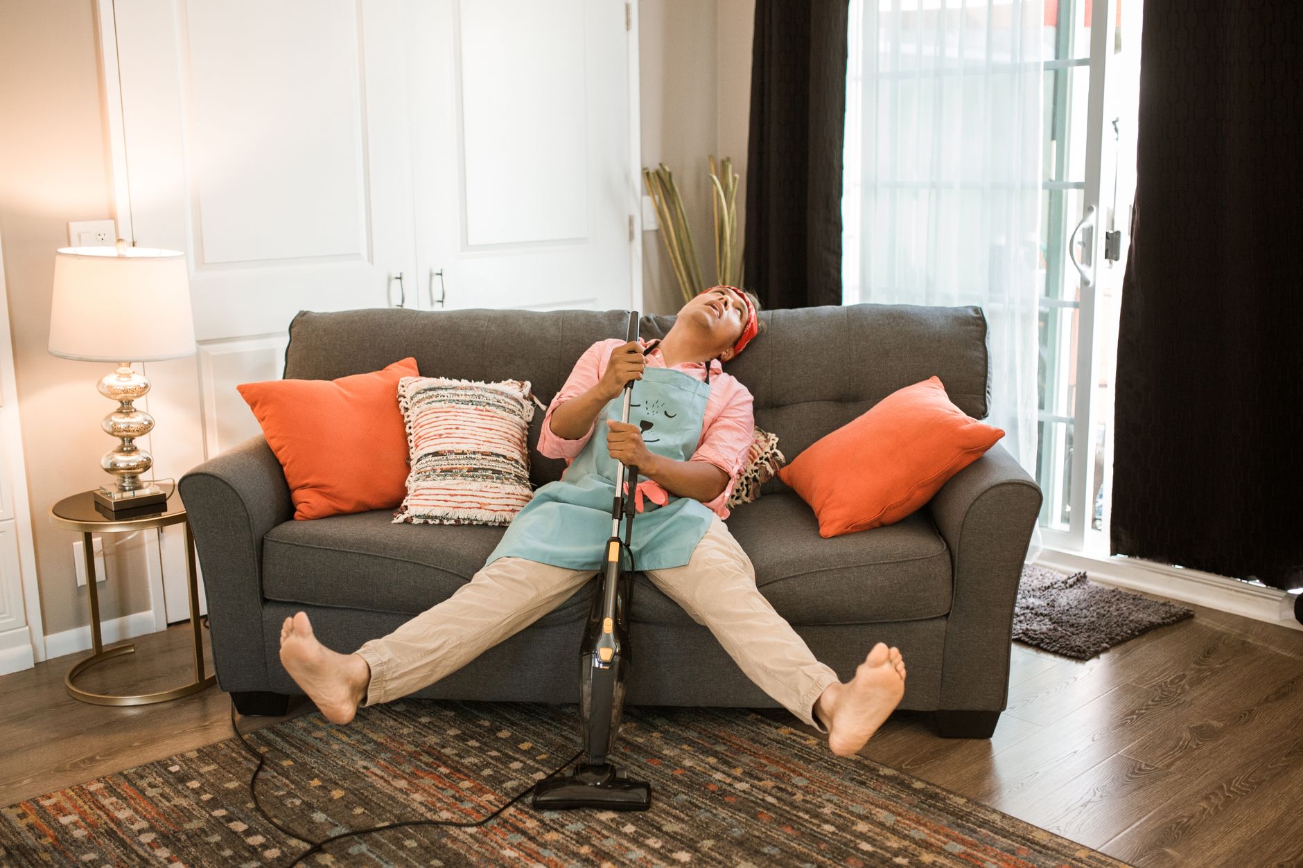 A mom sitting on the couch with a paper planner and a tablet, managing household chores.