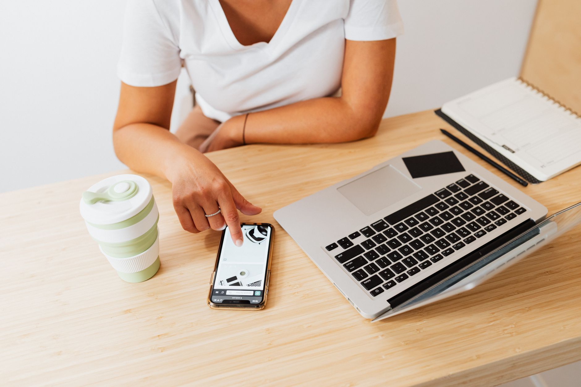 A mom sitting at a desk with a laptop and a tablet, syncing her digital planner with her phone.