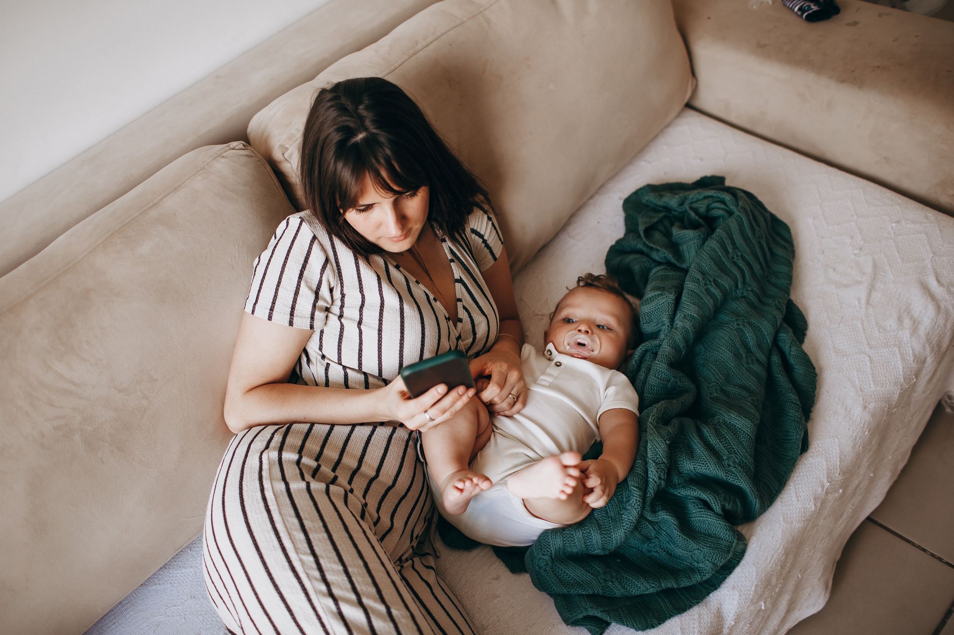 A mom sitting on the couch with a paper planner tracking baby milestones.