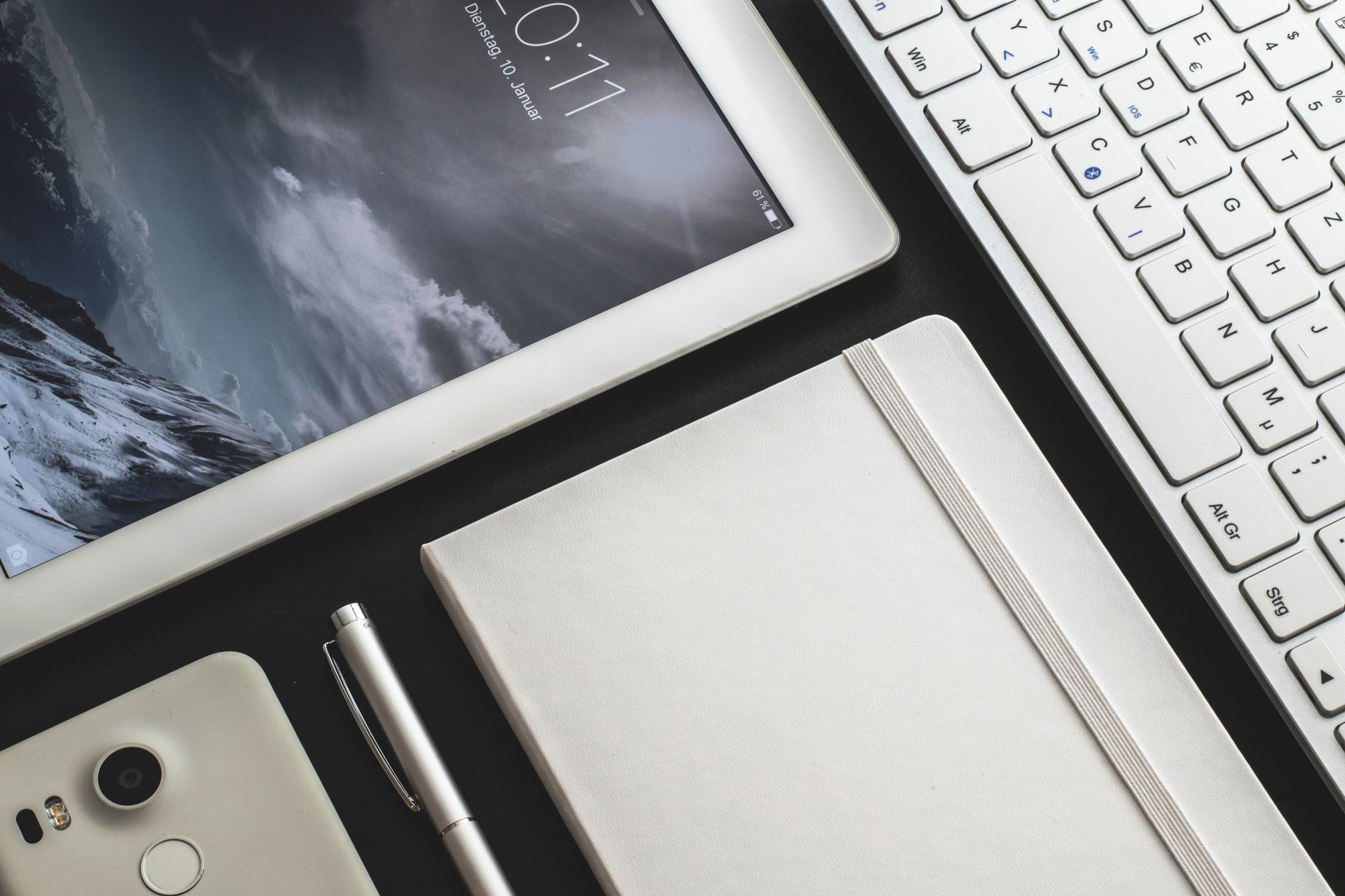 A mom sitting at a desk with a tablet and a notebook for meal planning.