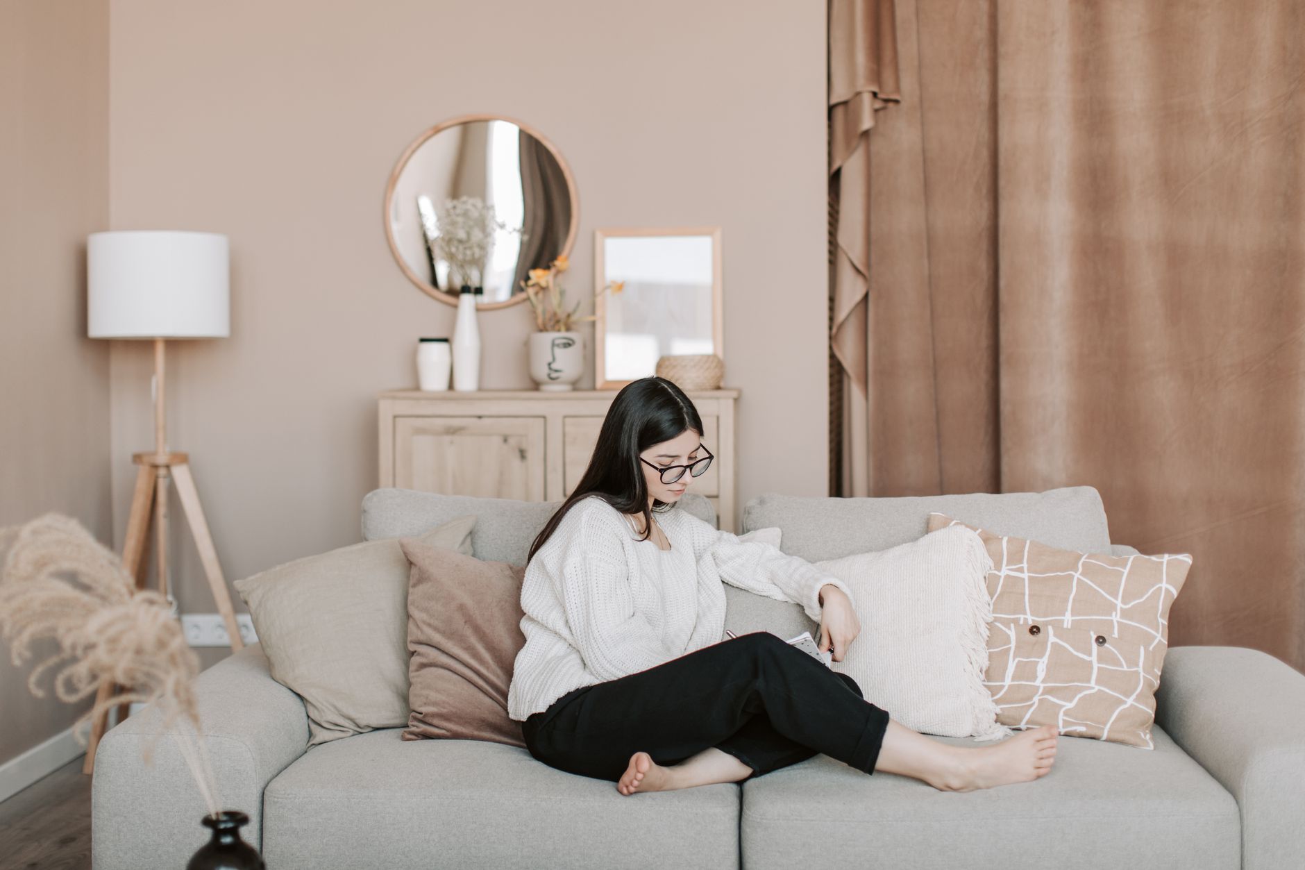 A mom sitting on the couch with a notebook filled with meal planning templates.