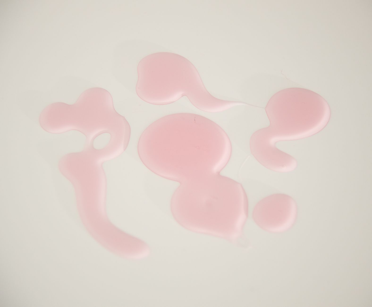 Soft pastel illustration of a pink watercolor droplet representing mild pink discharge in early pregnancy, with gentle lighting