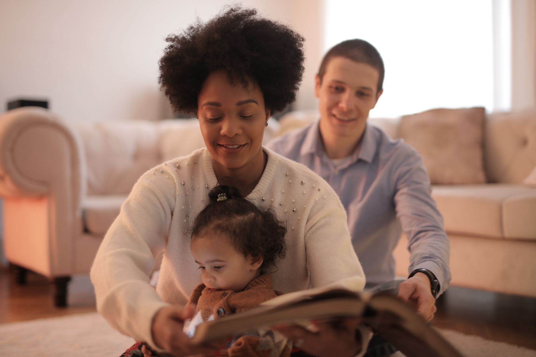 Mom reading to baby with another adult in the background