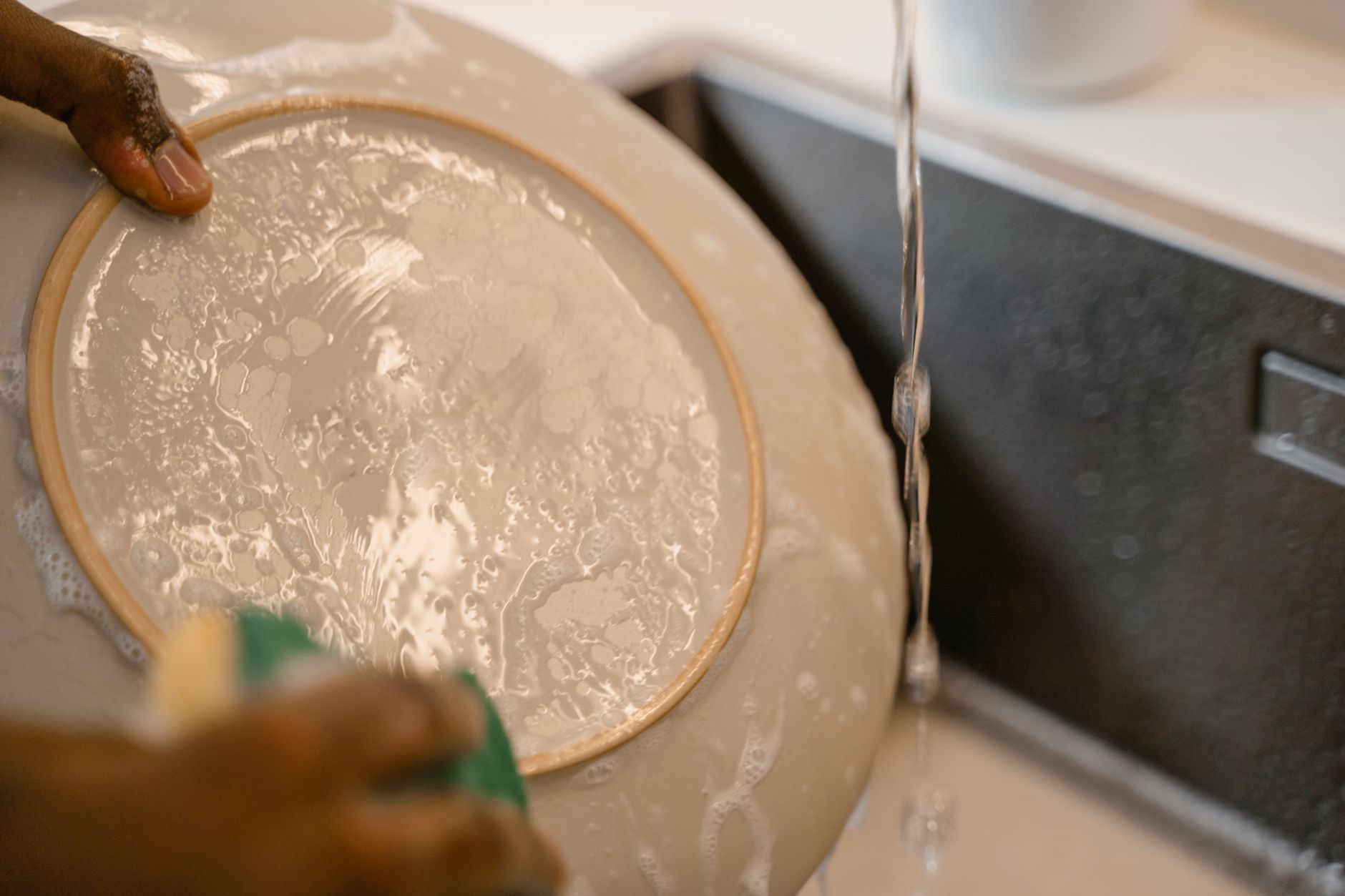 Close‑up of a Dockatot cover being gently hand‑washed in a basin with mild detergent, illustrating the recommended cleaning method for maintaining hygiene and fabric integrity.