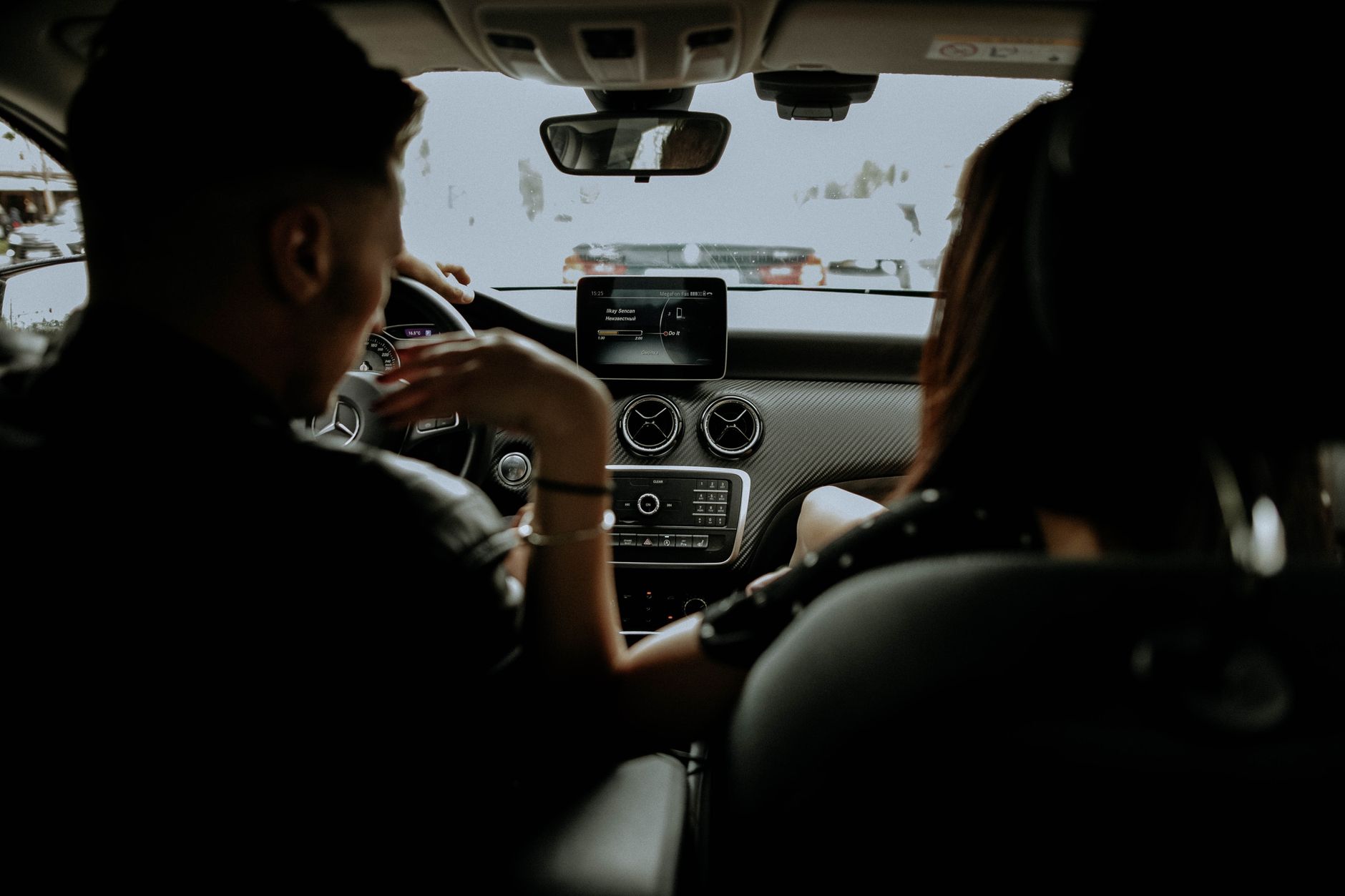 pregnant woman sitting comfortably in a rideshare vehicle, smiling, with a water bottle and a small pillow, illustrating a safe alternative to driving in late pregnancy