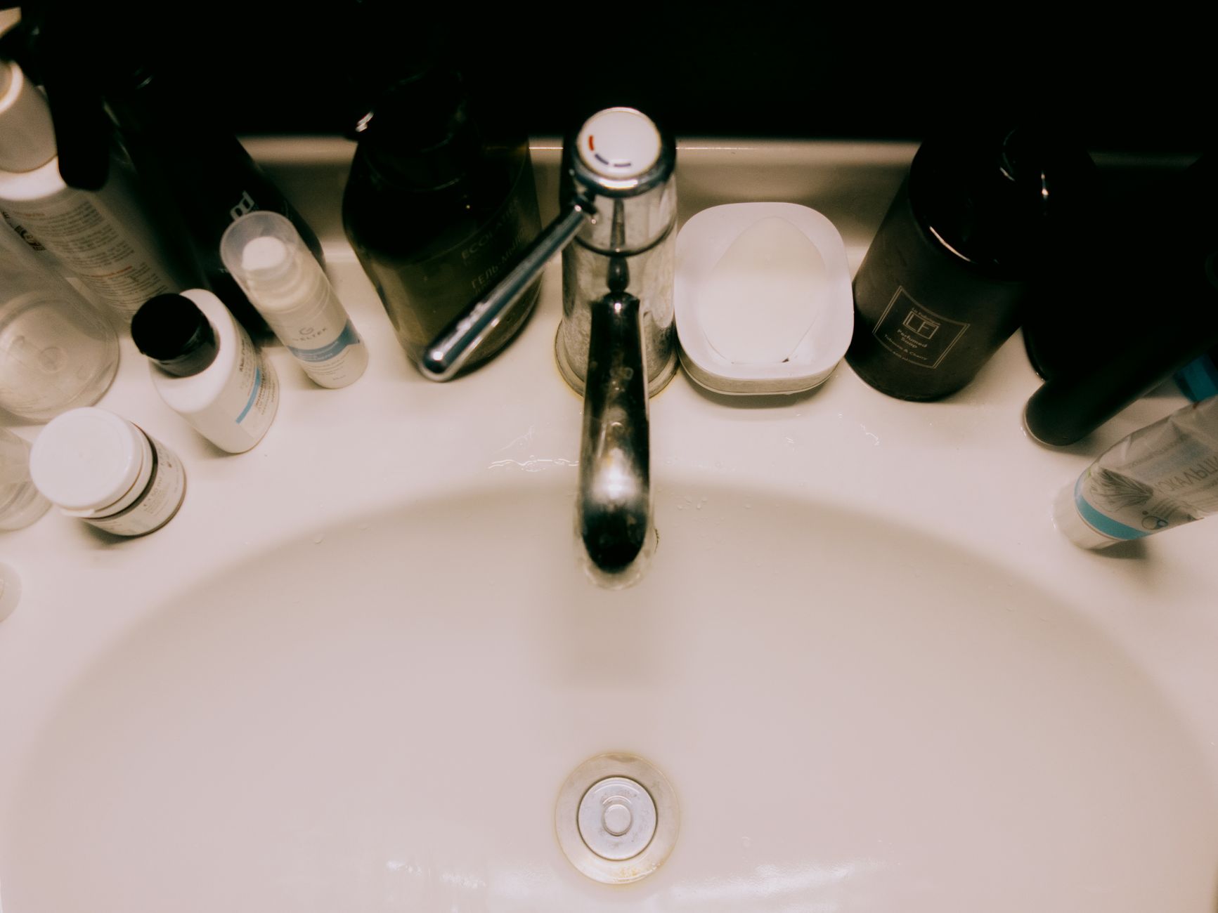 A soft‑light bathroom with a baby bathtub, a gentle towel, and a bottle of fragrance‑free lotion on a wooden shelf