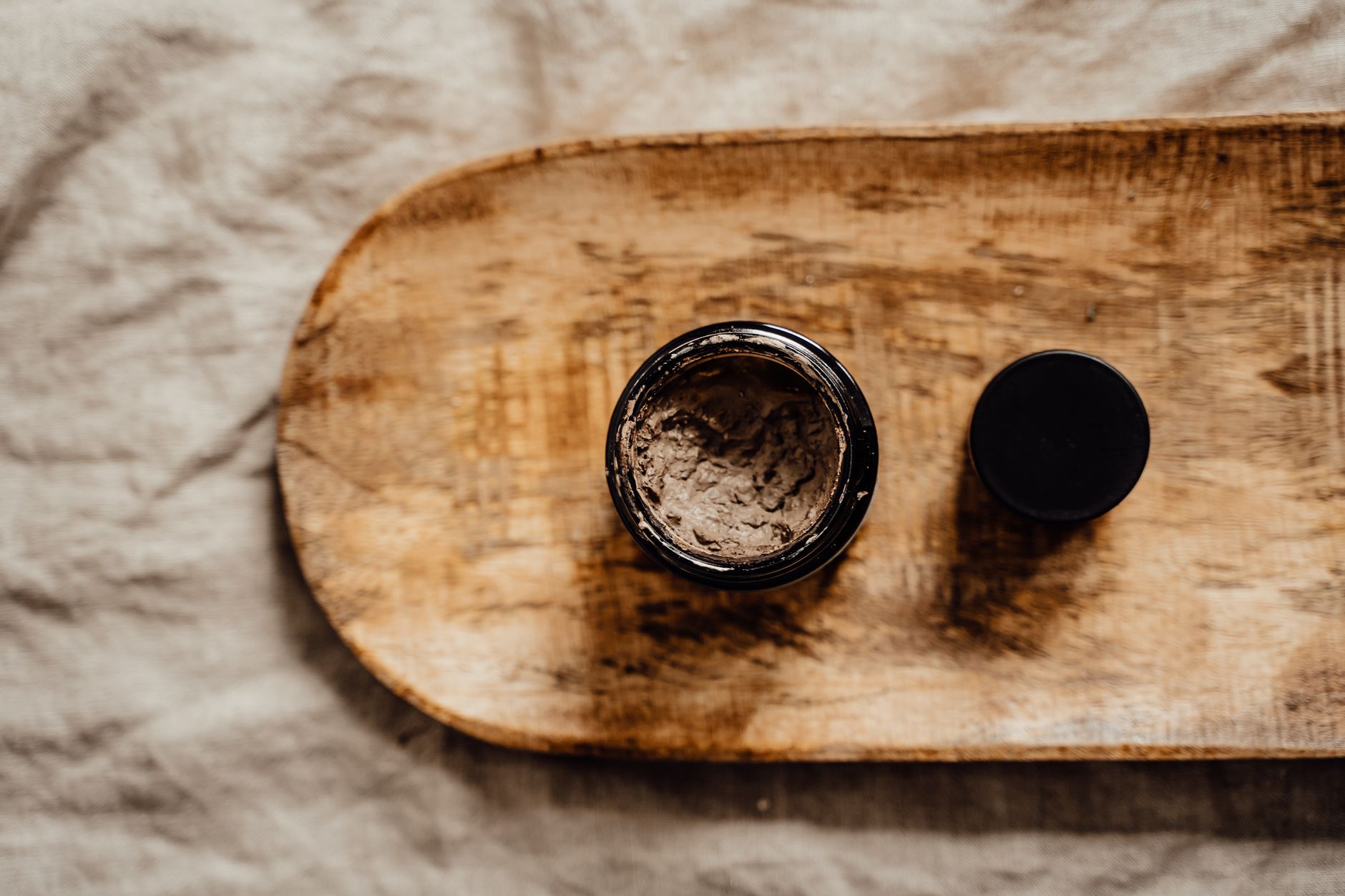 Close‑up of a small selection of pregnancy‑safe skincare products—almond oil, vitamin E capsule, and a gentle moisturizer—arranged on a wooden tray